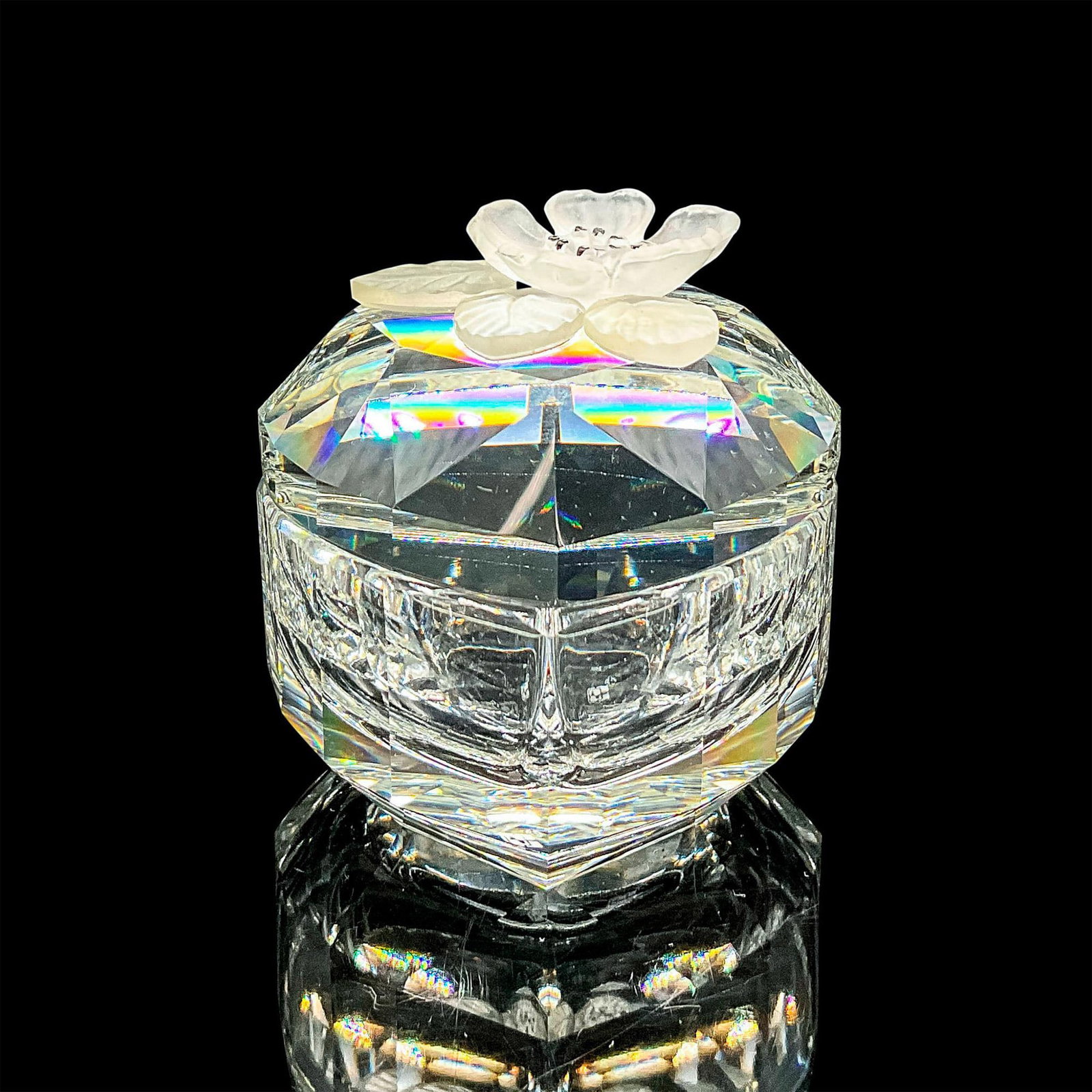 Swarovski Crystal Treasure Box, Heart Shaped w/Flower: Clear faceted crystal box with lid. A frosted flower and leaves adorn the lid. Retired. Swarovski mark. Item number 7465NR052000. This item has its original box: 4"H x 5"dia. Dimensions: 2.75"L x 1.75