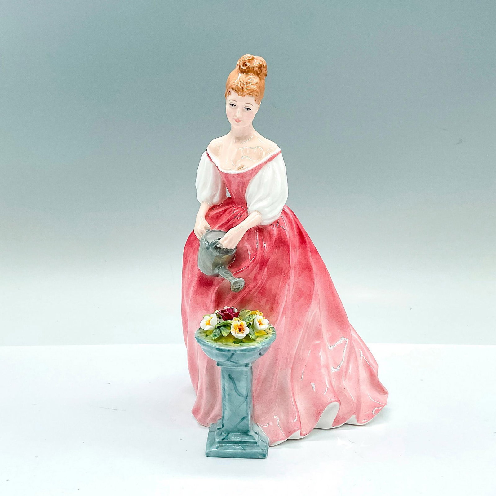 Alexandra - HN3292 - Royal Doulton Figurine: A glazed figure of a woman watering flowers. Pink and white coloration. Royal Doulton backstamp. Artist: Douglas V. Tootle Issued: c. 1994-2002 Dimensions: 5"L x 5"W x 8"H Manufacturer: Royal Doulton