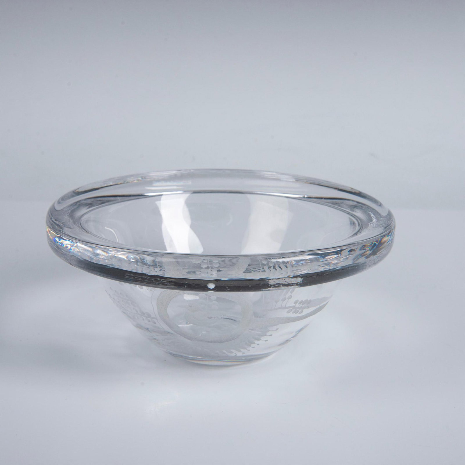 Kosta Boda by Goran Warff Stylized Bird Bowl: A clear bowl adorned with an engraving of a vintage style bird. Kosta Boda etched on the underside. Artist: Goran Warff Dimensions: 7.5"W x 3.25"H Manufacturer: Kosta Boda Country of Origin: Sweden
