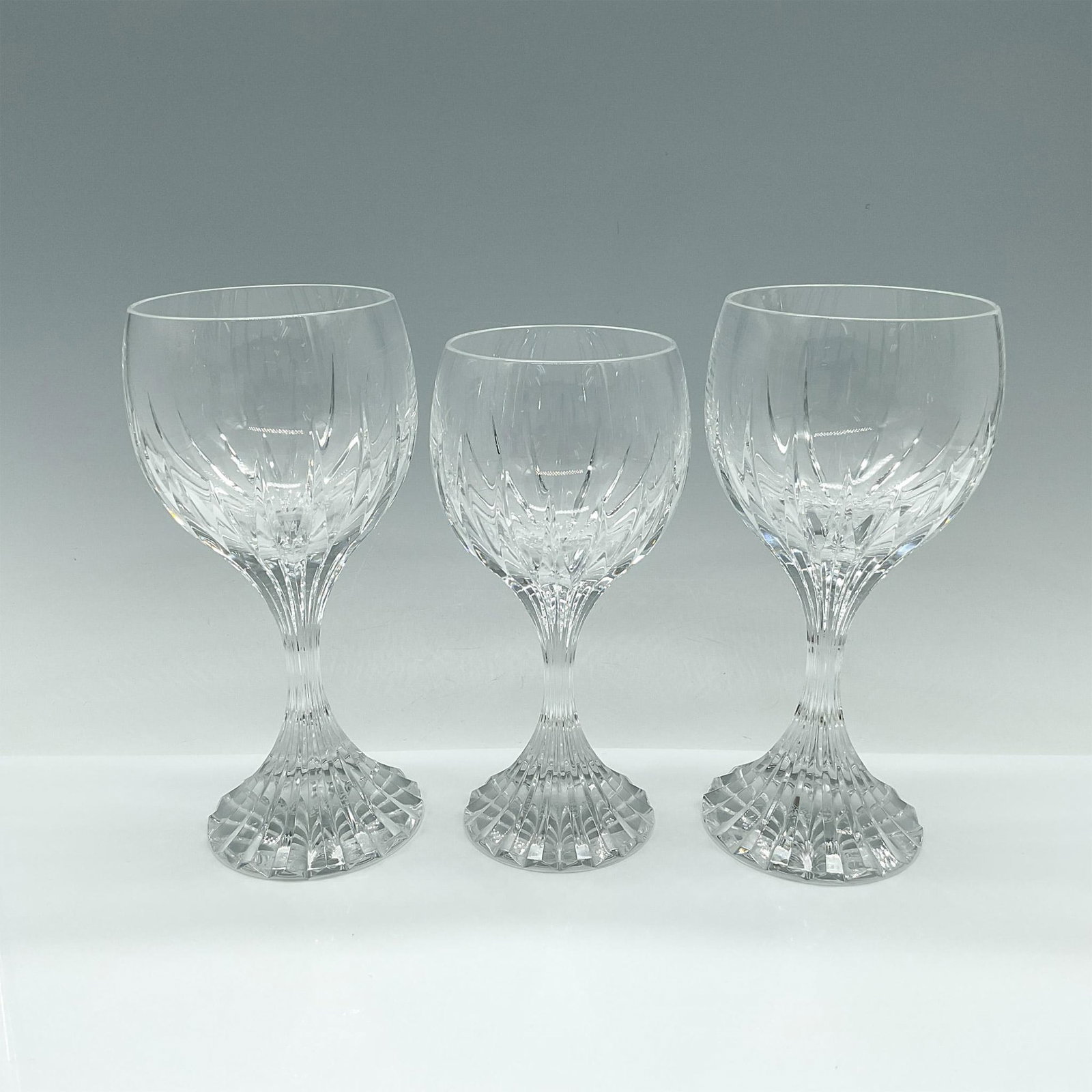3pc Baccarat Crystal Wine Glasses, Massena Pattern: Handcrafted of full-lead crystal, the Massena pattern showcases deep beveled cuts that create a captivating prismatic effect. Its defining feature is the vertical cuts extending from the base to the b