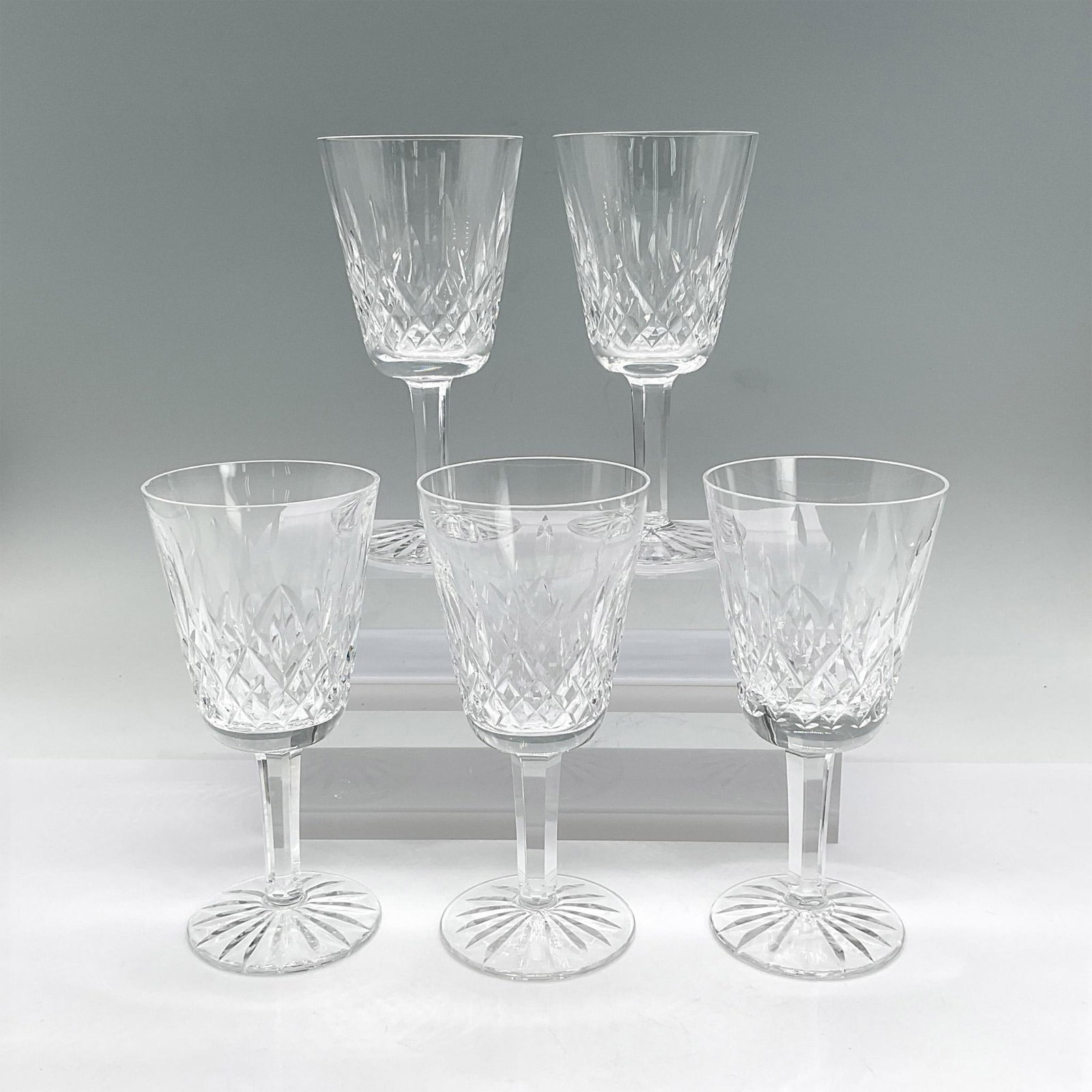 5pc Waterford Crystal White Wine Glasses, Lismore: Five clear stemmed crystal glasses with crisscross, leaf and sunburst etched design. Waterford mark. Dimensions: 5.5"H x 2.5" dia Manufacturer: Waterford Country of Origin: Ireland