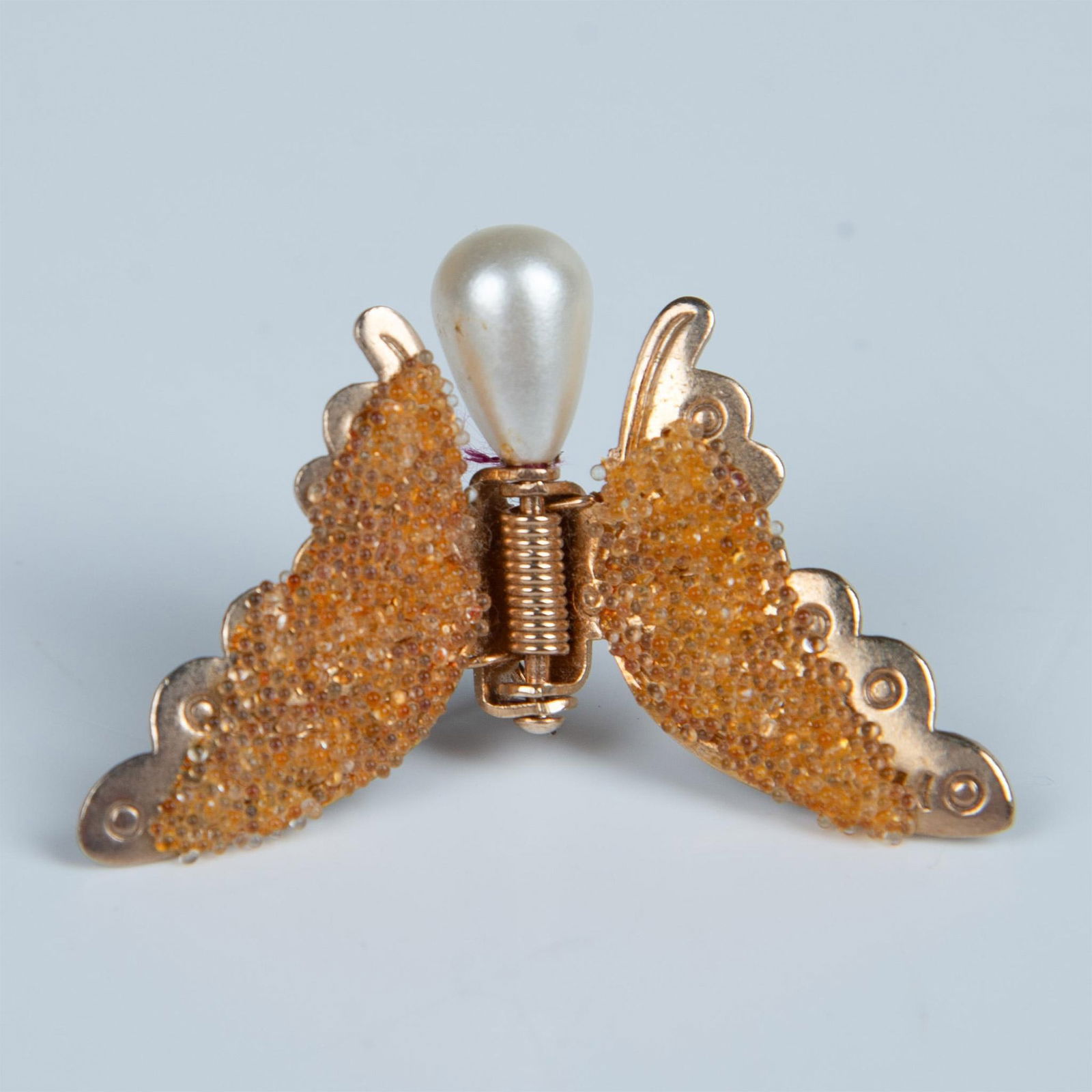 Cute Gold Metal Faux Pearl Butterfly Clip-On Pin: Beautiful butterfly pin with spring-loaded glittery gold tone wings. Dimensions: 1.25"L x 1.75"W