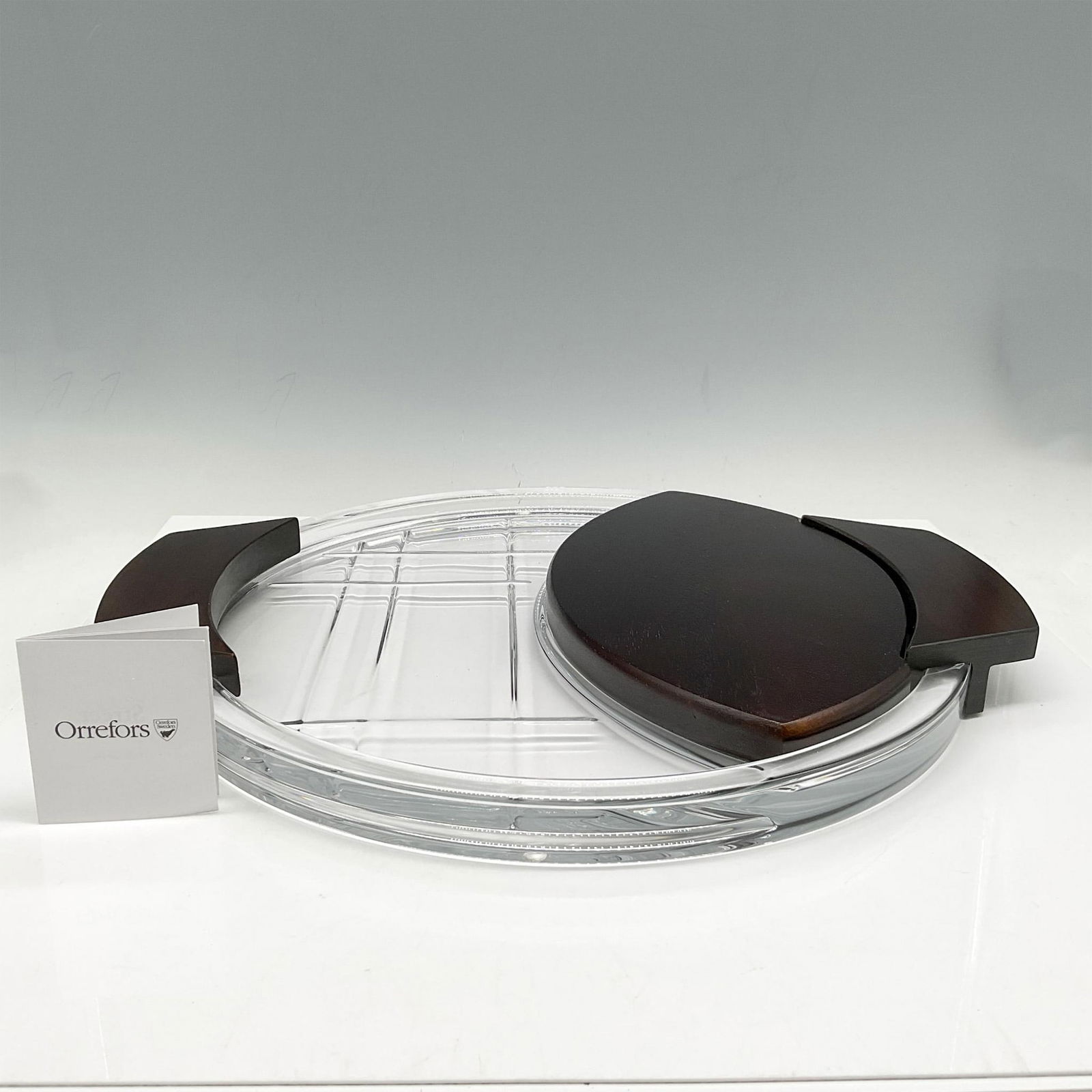Orrefors Crystal & Wood Cheese Platter, Street Collection: Layered crystal round platter with dark wood handles and separate wood cheese board. Orrefors acid and sticker mark. This item has its original box: 15"L x 15"W x 3"H. Issued: 21st century Dimensions: