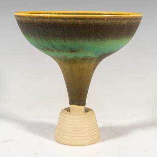 Gustavsberg by Wilhelm Kage Stoneware Farsta Vase: A green mottled glazed funnel form vase with black, blue, and amber speckles, and a ridged base. Gustavsberg stickered. Artist signed. Farsta impressed on the underside. Artist: Wilhelm Kage Issued: 2