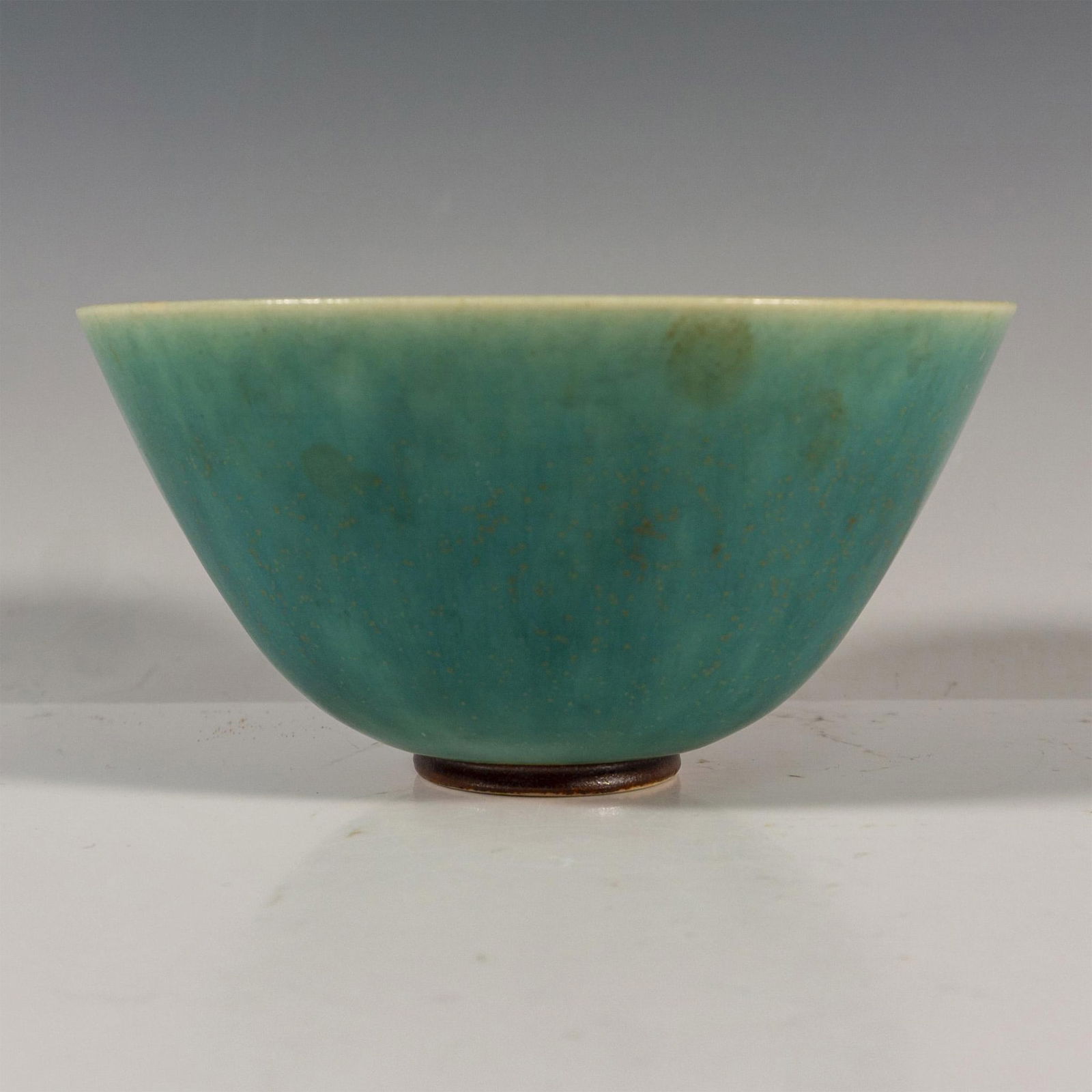 Saxbo Stoneware Glazed Bowl: A small blue-green glazed bowl with gilded speckles. Saxbo Denmark impressed on the underside. Issued: 20th century Dimensions: 5"W x 2.5"H Manufacturer: Saxbo Country of Origin: Denmark