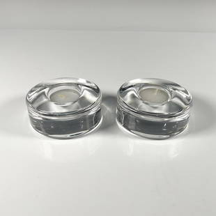 2pc Orrefors Crystal Candleholders, Puck: Circular clear thick crystal duo, each include tealights, their certificates and the original boxes, dimensions: 4''L x 4''W x 2''H. Orrefors etched backstamp. Artist: Lena Bergstrom Dimensions: