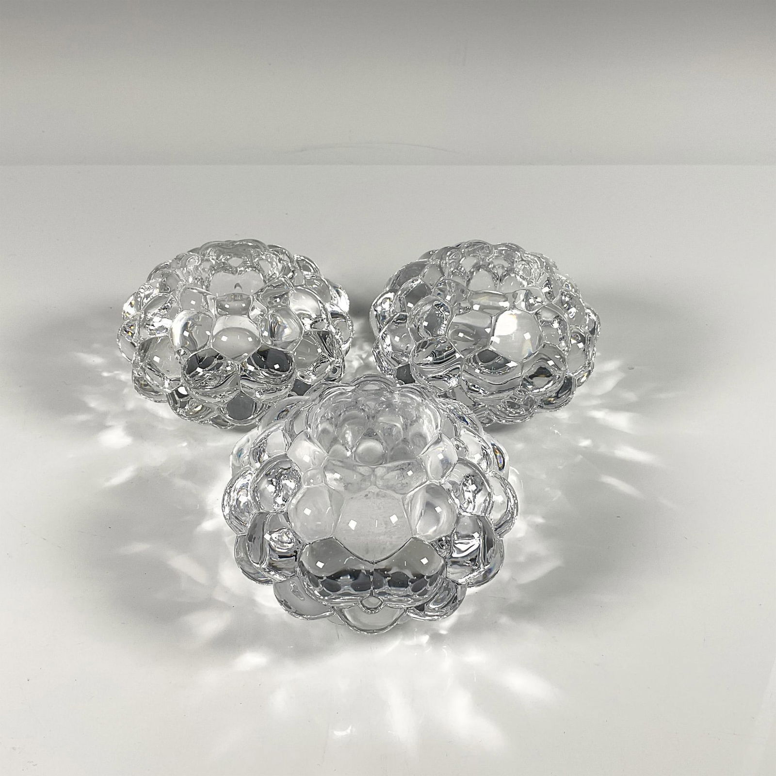 3pc Orrefors Crystal Candleholders, Hallon Raspberry: Trio of thick clear crystal in the raspberry pattern. Orrefors etched backstamp. Includes certificate and their original boxes, dimensions: 4.5''L x 4.5''W x 3''H. Artist: Anne Nilsson Dimensions: 3''