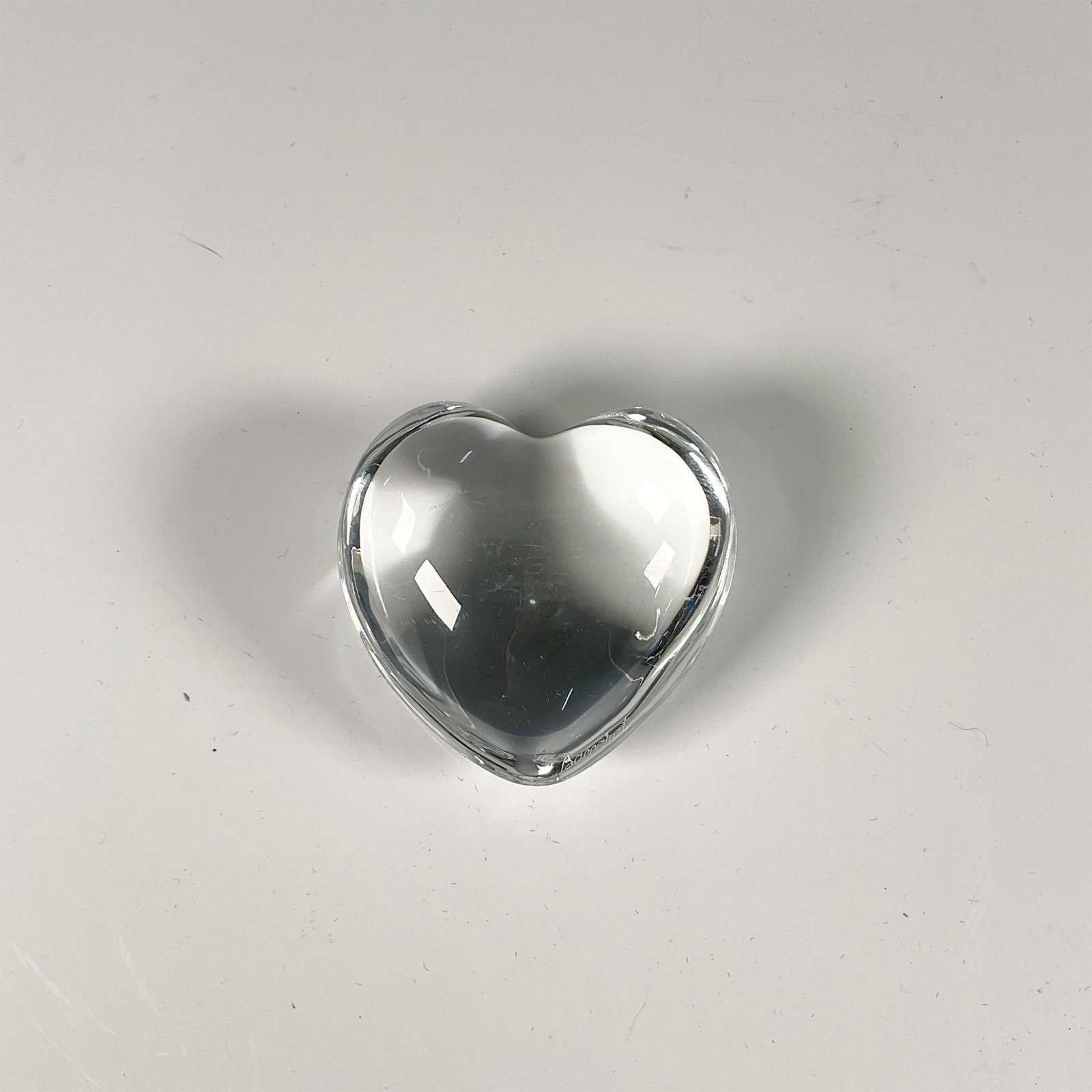 Baccarat Crystal Heart Paperweight: A clear heart figure. Baccarat etched markings. Issued: 20th century Dimensions: 3"L x 2.75"W x 1.25"H Manufacturer: Baccarat Country of Origin: France