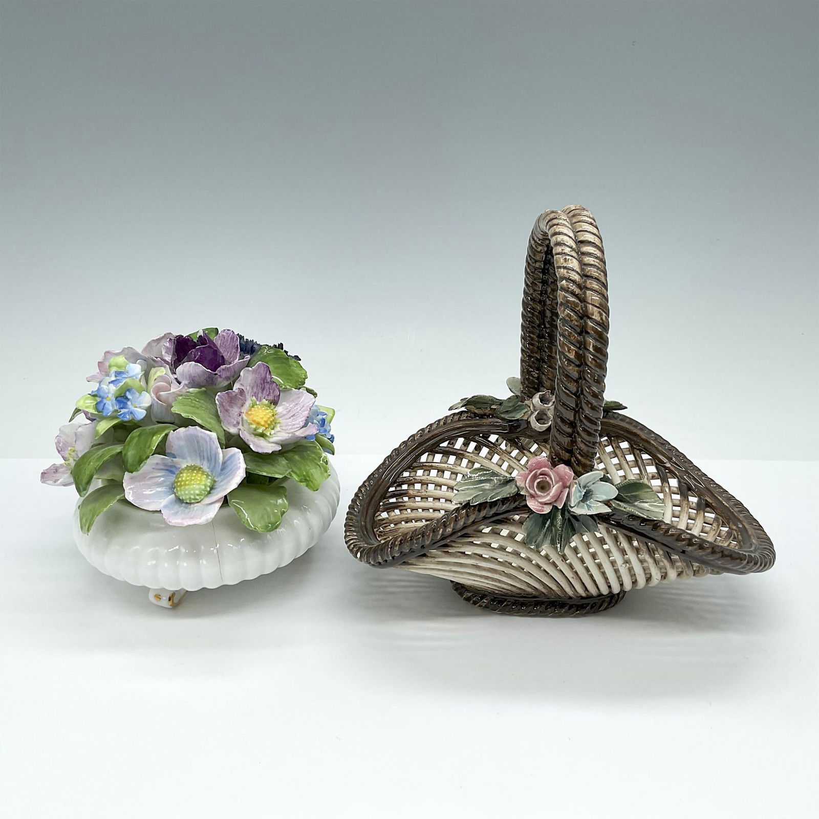 2pc Capodimonte and Royal Adderley Floral Porcelain Baskets: This charming grouping features a Capodimonte basket with warm brown tones and a woven design, embellished with delicate flowers, measuring 6.5"L x 4"W x 6"H. Additionally, included is a Royal Adderle