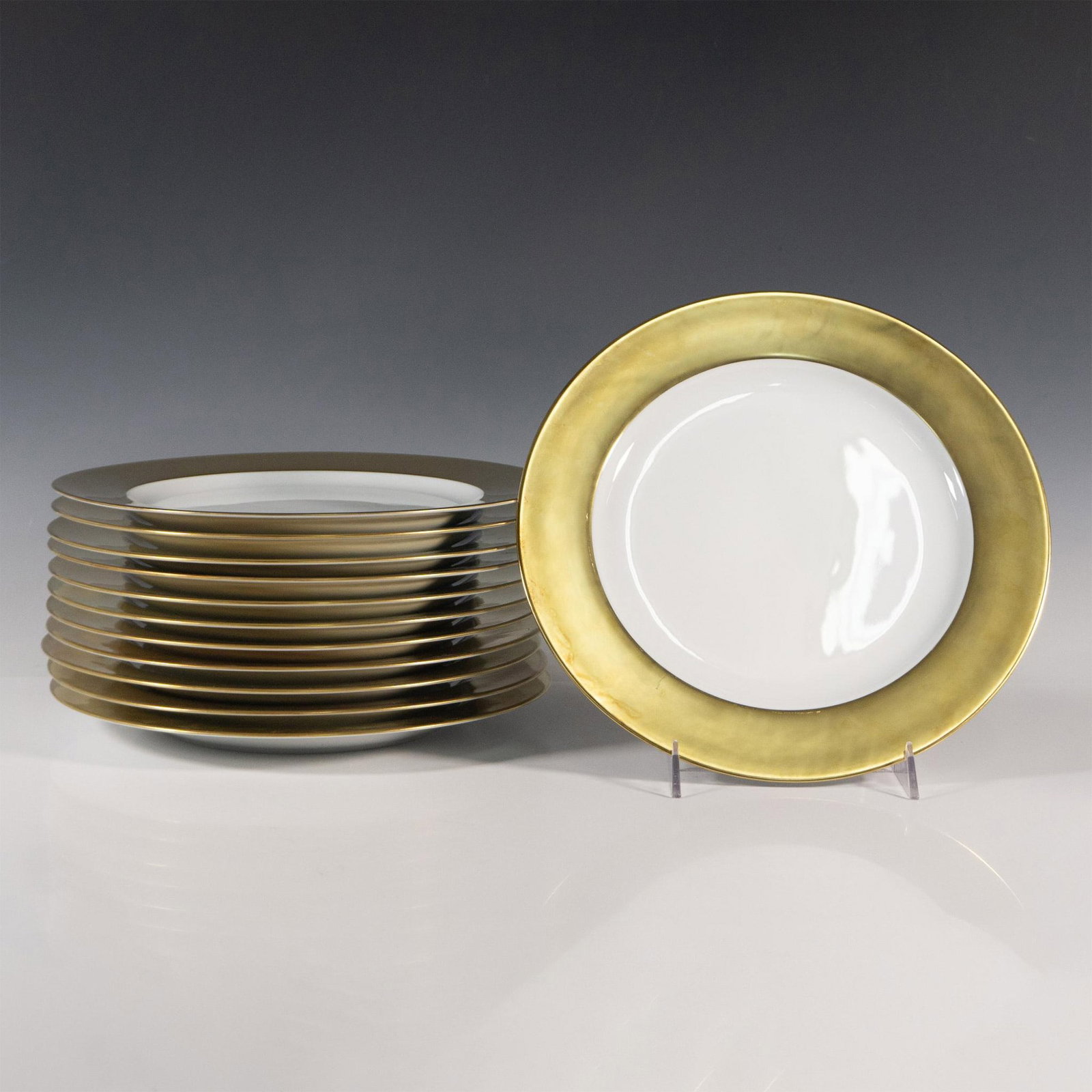 12pc Bernardaud Limoges Gold-Rimmed Dinner Plates: Twelve large golden-rimmed dinner plates marked Bernardaud Limoges France on the bottom. Dimensions: 11.5"dia. Manufacturer: Bernardaud Country of Origin: France