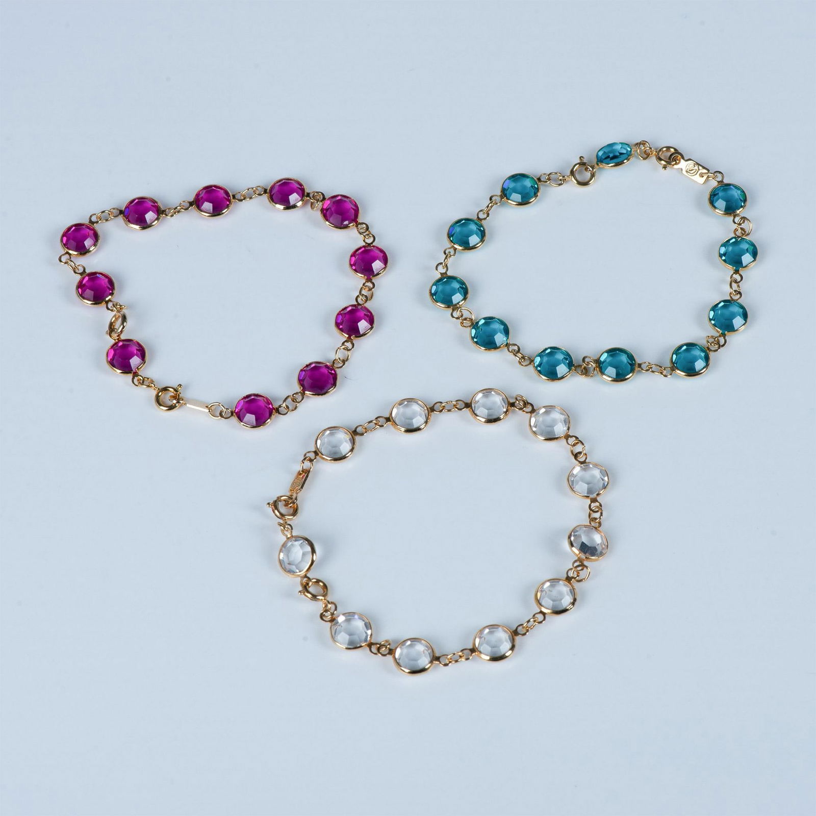 3pc Swarovski Teal, Pink & Clear Crystal Link Bracelets: Three gold-plated link bracelets set with different colored crystals. Each bracelet measures 7.5"L and includes an extra link to extend it approximately 1". Swarovski swan marks stamped near clasps. C