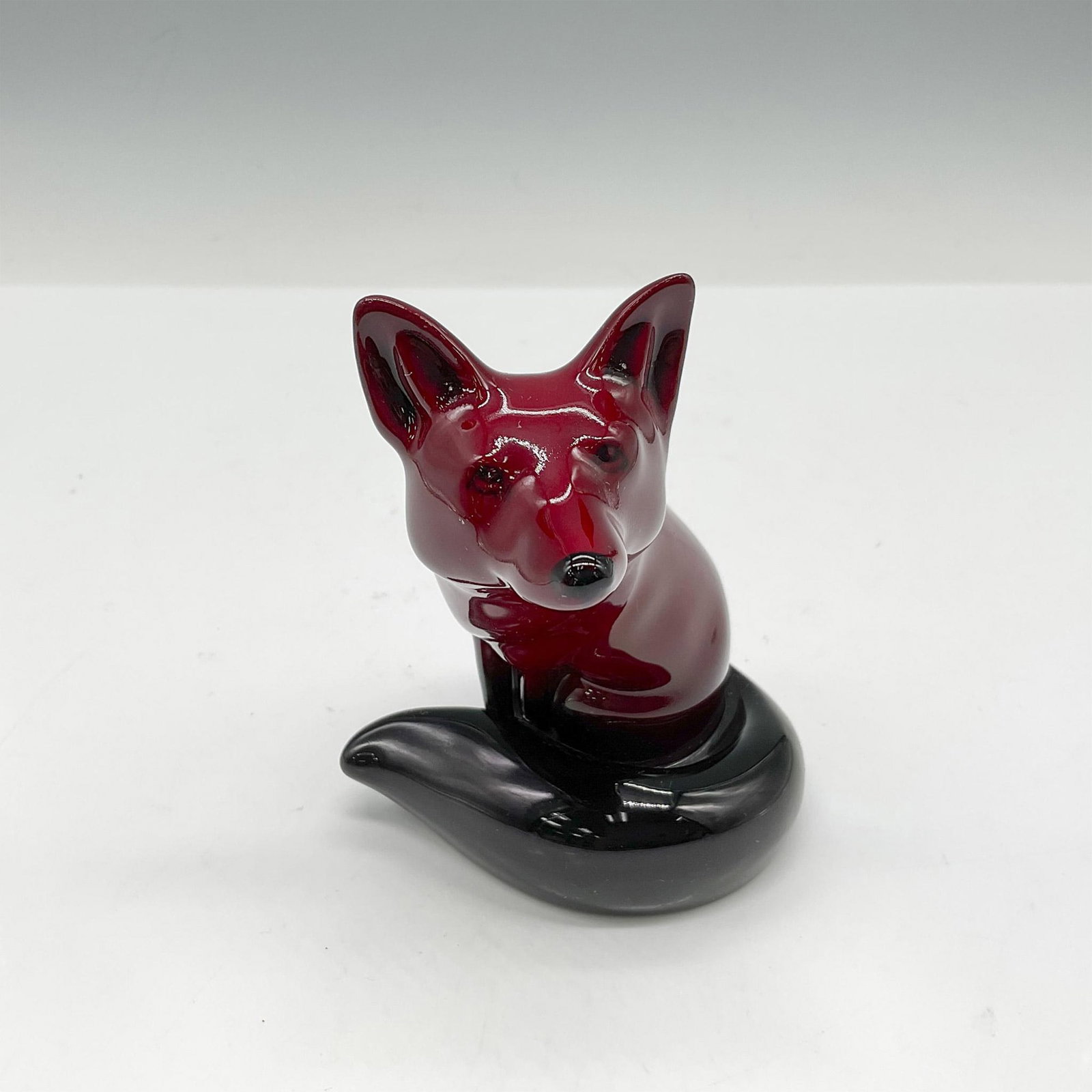 Royal Doulton Flambe Figurine, Seated Fox HN147B: Flambe finished with long curled tail. Royal Doulton backstamp. Issued: 1918 - 1946 Dimensions: 3.25"L x 4"W x 4.25"H Manufacturer: Royal Doulton Country of Origin: England