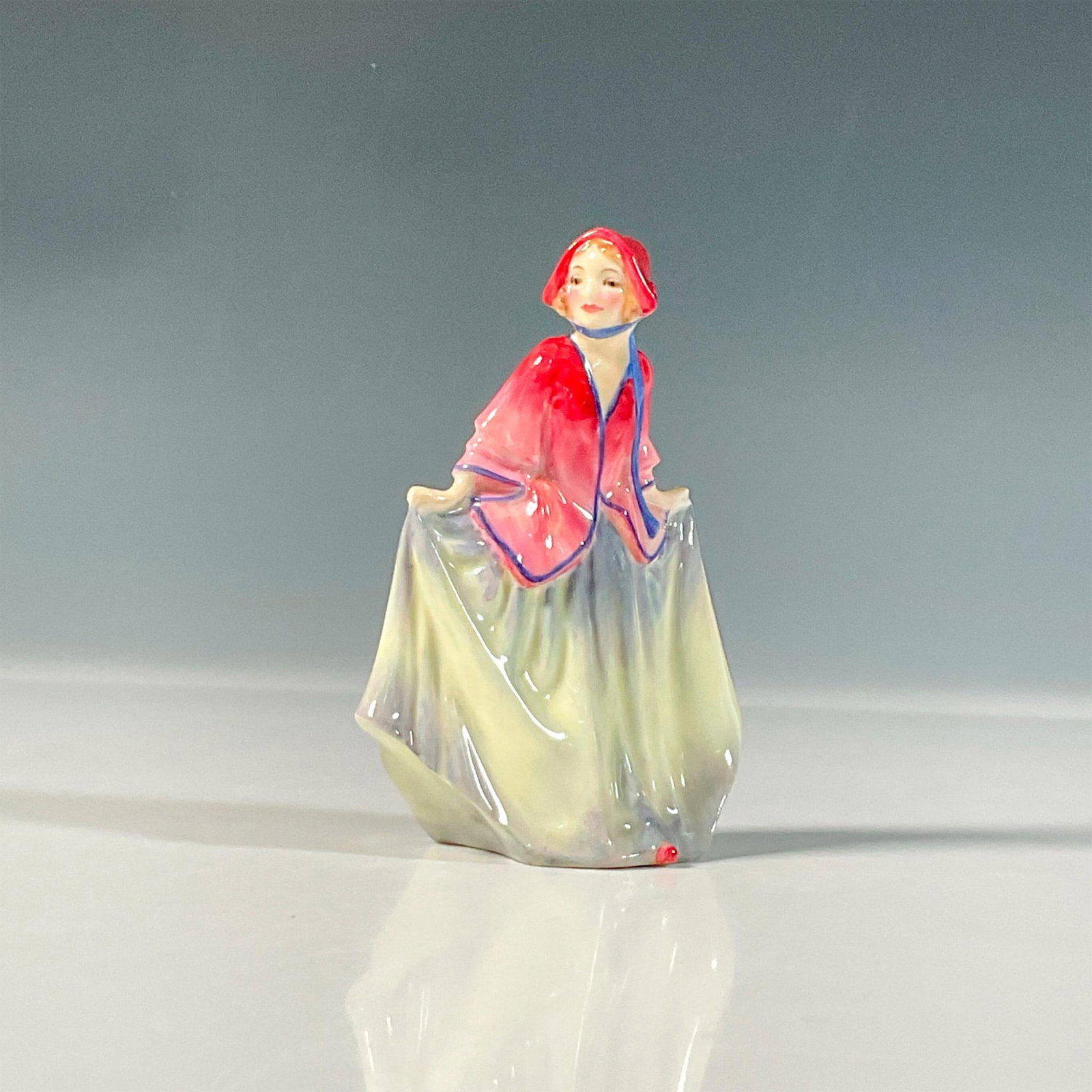 Sweet Anne M27 - Royal Doulton Mini Figurine: Red bonnet and matching blouse elegantly paired with a yellow and blue skirt. Royal Doulton backstamp. Artist: Leslie Harradine Issued: 1932-1945 Dimensions: 2.75"L x 1.75"W x 4"H Manufacturer: Royal 