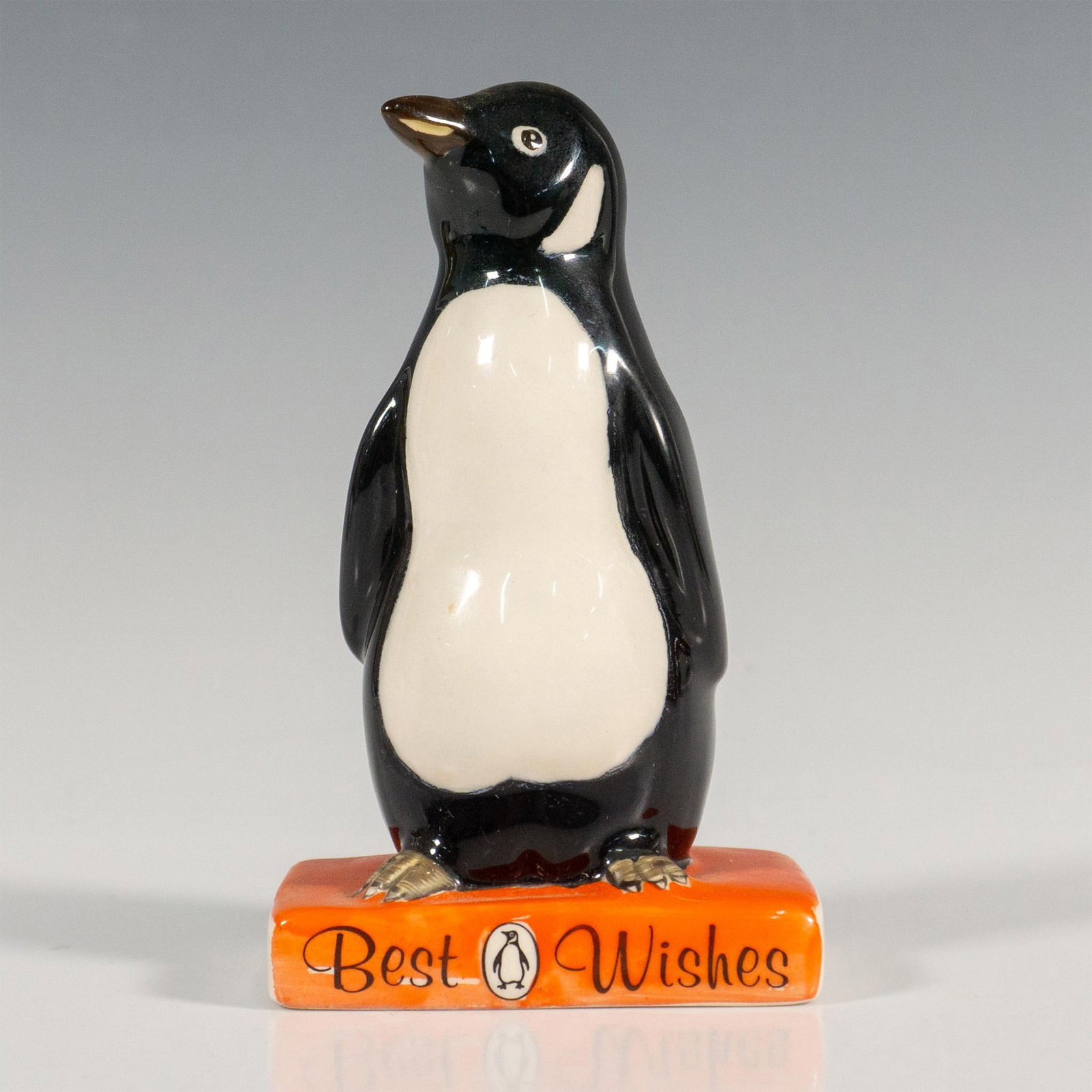 Best Wishes Penguin - Royal Doulton Advertising Figurine: Commissioned advertising for the British Publishing House Penguin Books, hand painted figurine of a penguin standing on an orange book Best Wishes. Gloss finish. Backstamp Royal Doulton 90 in black. I