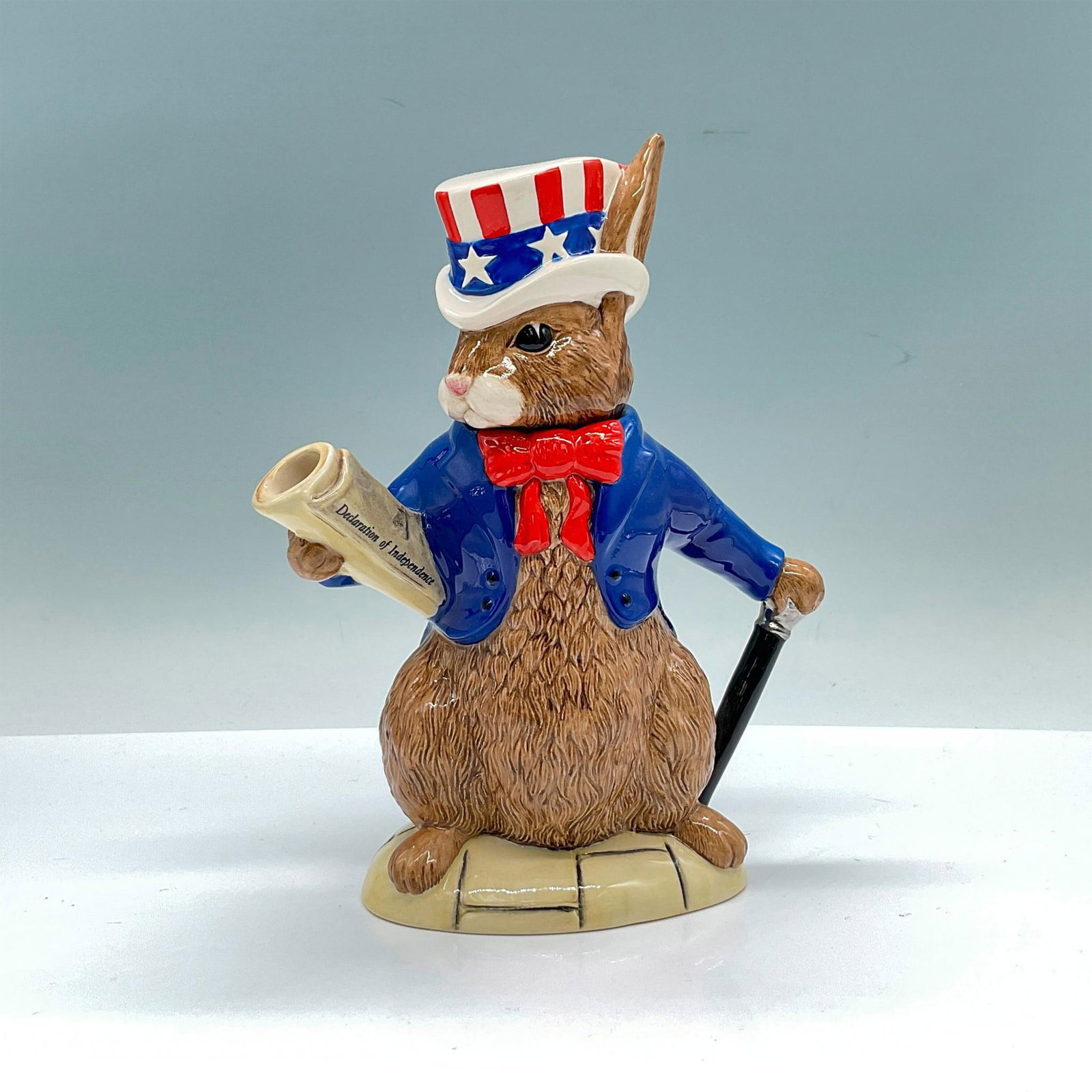 Royal Doulton Bunnykins Lidded Teapot, U.S.A President D6996: Special edition of 2500 glossy porcelain with removable lid headpiece, features a patriotic bunny dressed in a blue jacket and red bow tie, with a top hat styled after the American flag, holding a new