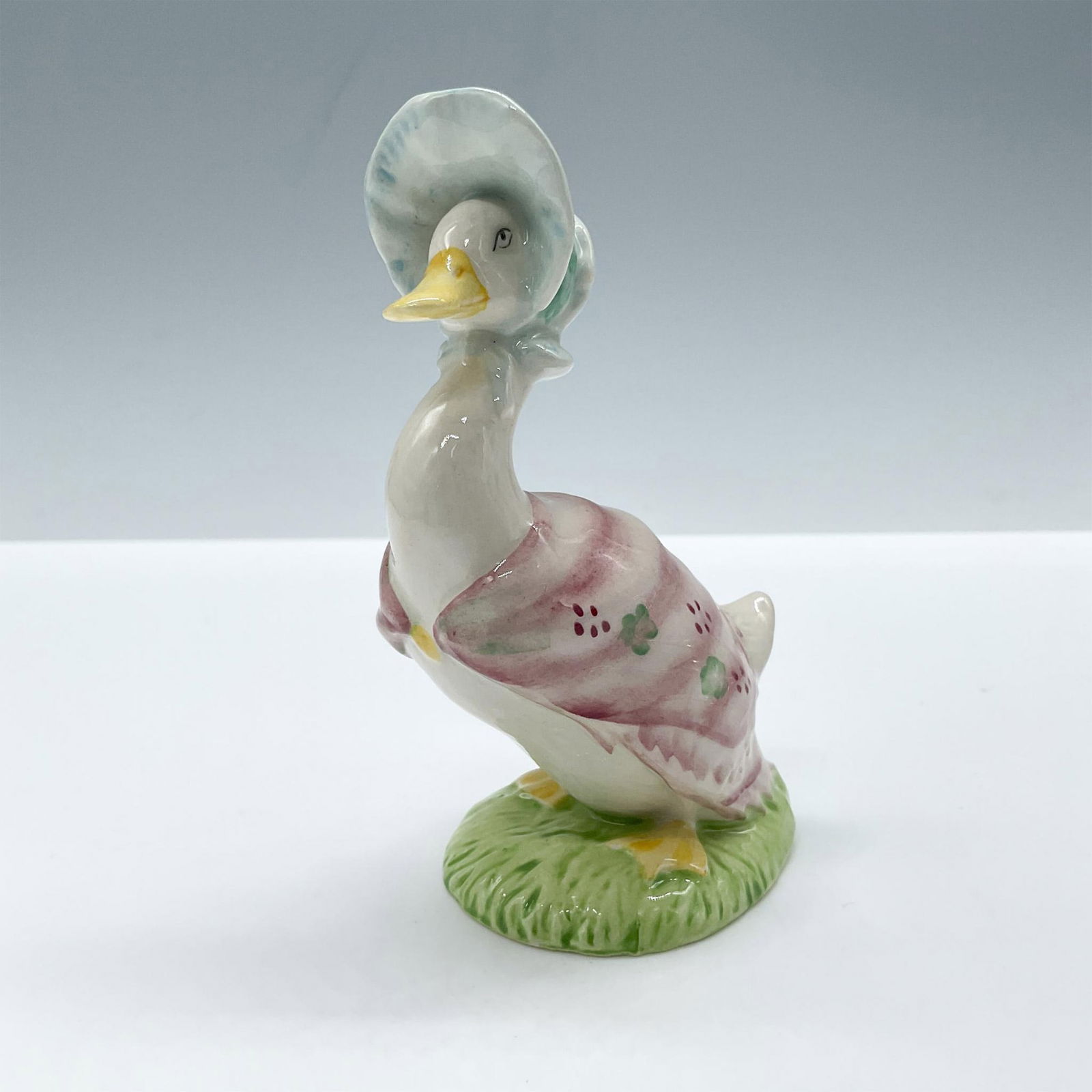 Royal Albert Beatrix Potter Figurine, Jemima Puddleduck: Glossy porcelain, duck is wearing a blue hat and a pink shawl decorated with green and red flowers. Royal Albert backstamp. Includes the original box, dimensions: 2''L x 2.25''W x 5''H. Issued: c. 198