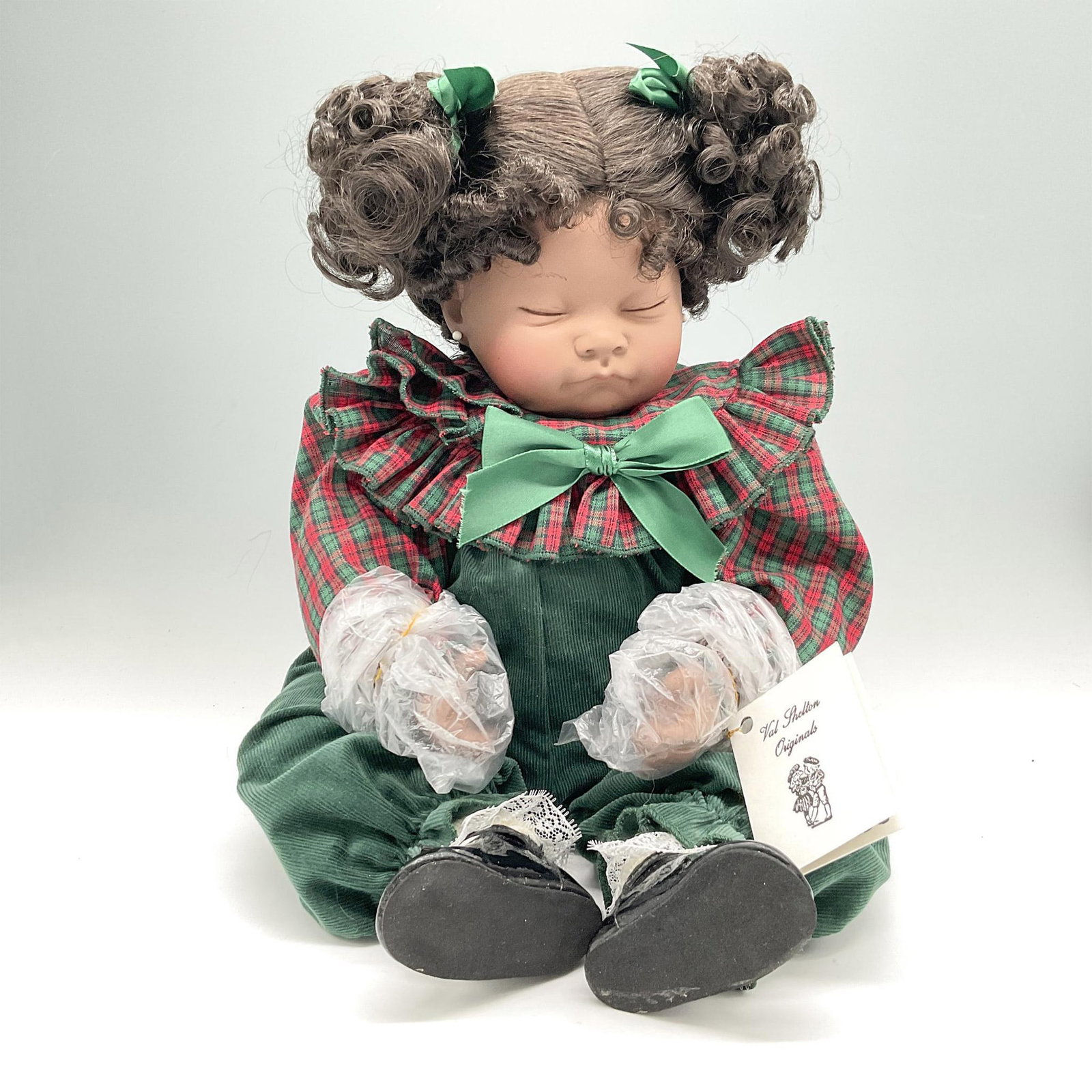 Val Shelton Porcelain Royal Vienna Dolls, Reasee: New in original packaging. Sleeping dark skinned baby with curly pigtails with green bows in her hair, wearing green corduroy jumper with red and green plaid collar and black patent leather shoes. Lim