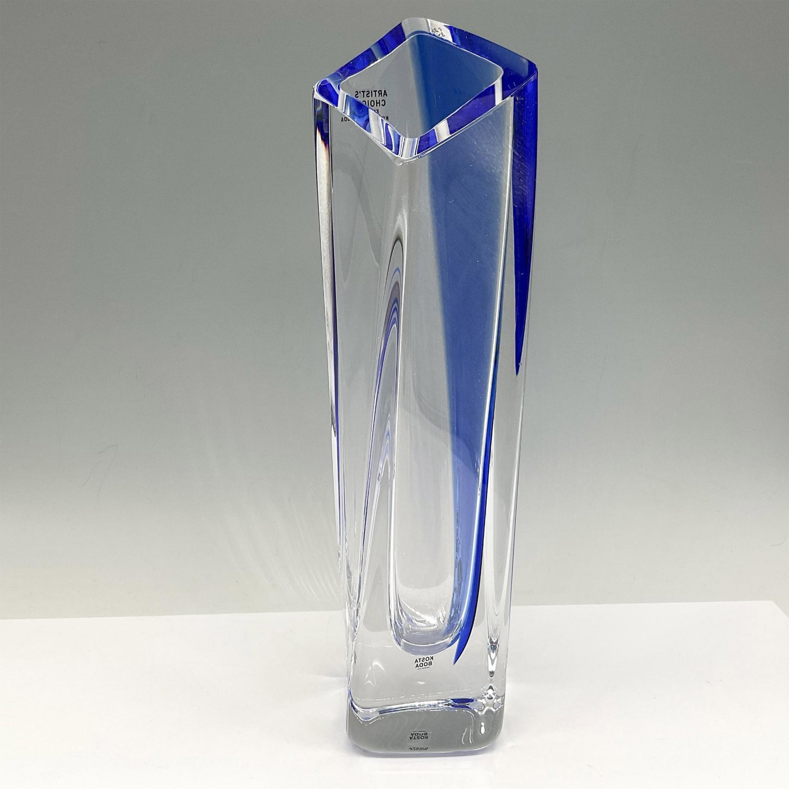 Goran Warff for Kosta Boda Blue Angled Vase, Signed: Blue crystal blended with clear to create a distinctive presentation. Signed by artist. Marked artist choice. Kosta Boda mark. Artist: Goran Warff Issued: 21st century Dimensions: 2.5"L x 2.5"W x 12"H