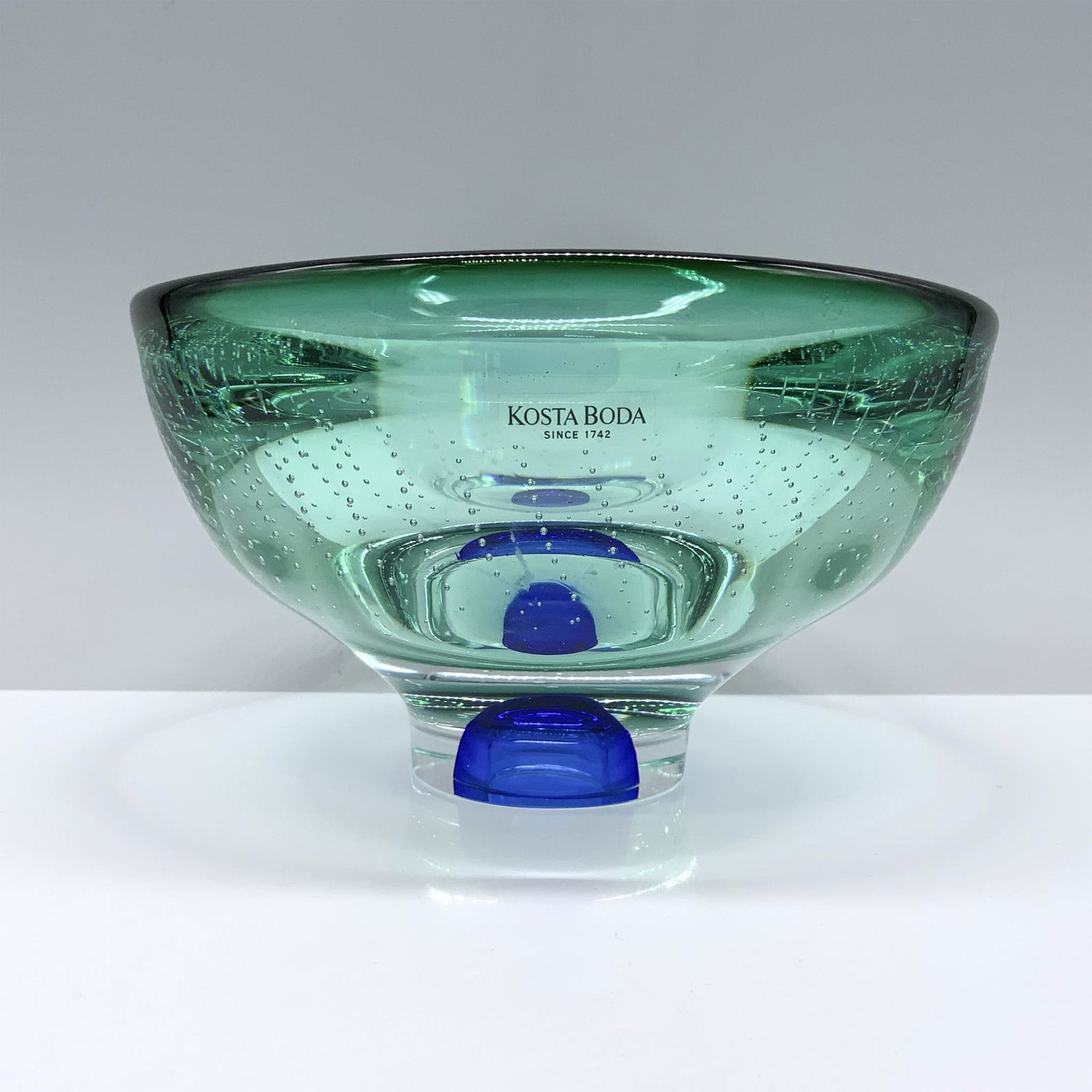 Goran Warff for Kosta Boda Crystal Art Bowl, Teal: A teal oval crystal bowl featuring air bubble decorations and a cobalt blue base. Marked Kosta Boda. Model number 59910. Artist: Goran Warff Dimensions: 5.75"L x 5.25"W x 3.5"H Manufacturer: Kosta Bod