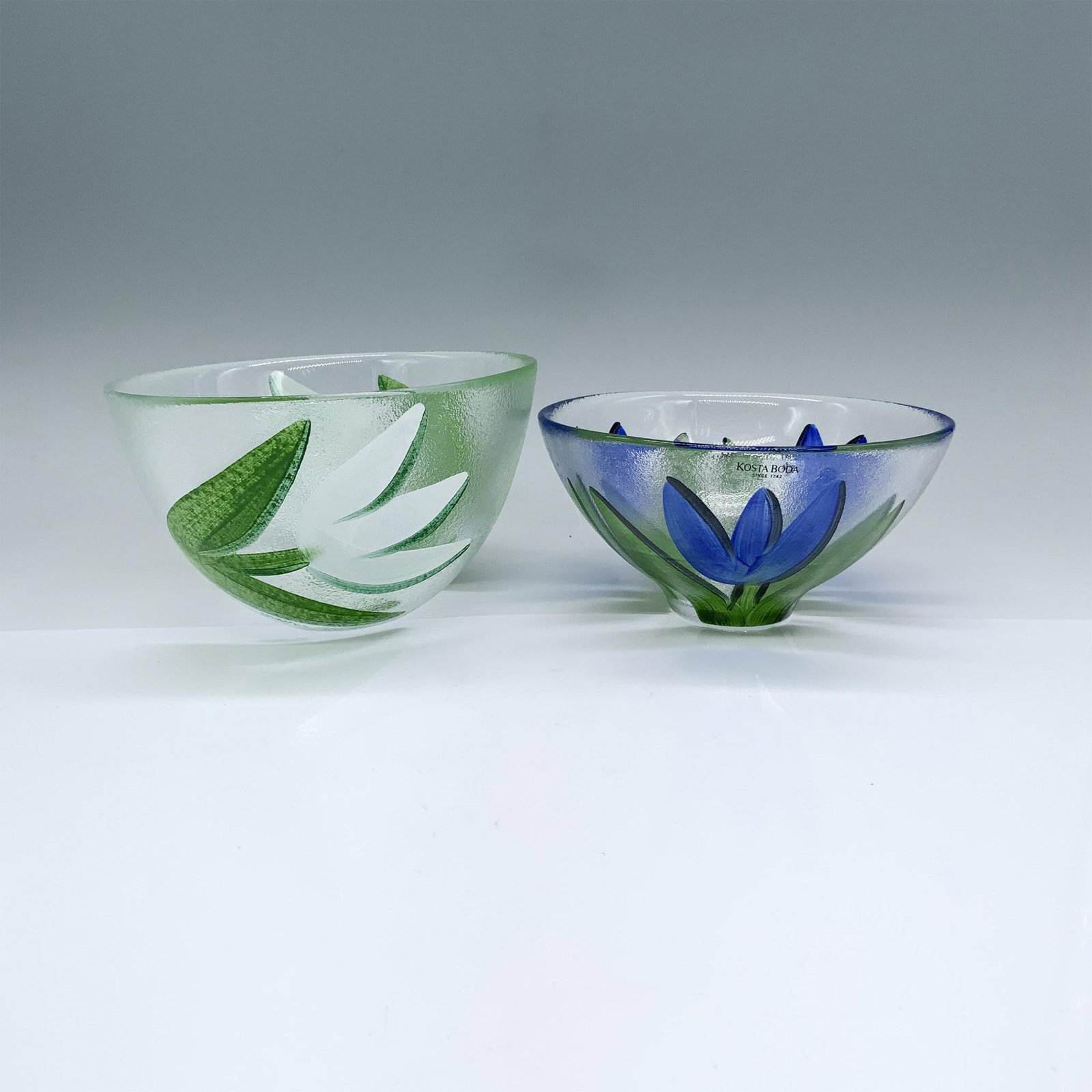 2pc Kosta Boda by Ulrica Hydman Vallien Tulipa Bowls: Beautiful hand painted bowls designed by Ulrica Hydman Vallien. The larger one with white tulip flowers is marked UHV/BS and measures 5.75"dia. x 3.5"H. The smaller one with blue tulip flowers is mark