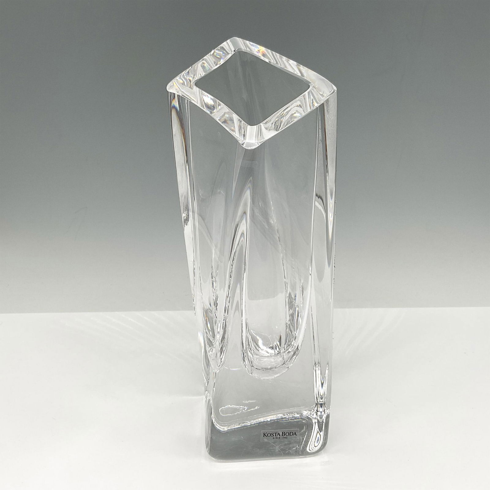 Goran Warff for Kosta Boda Angled Vase, Signed: Clear crystal with angled rim with slightly twisted base. Signed by Artist. Kosta Boda mark. Artist: Goran Warff Issued: 21st century Dimensions: 2.5"L x 3"W x 9"H Manufacturer: Kosta Boda Country of