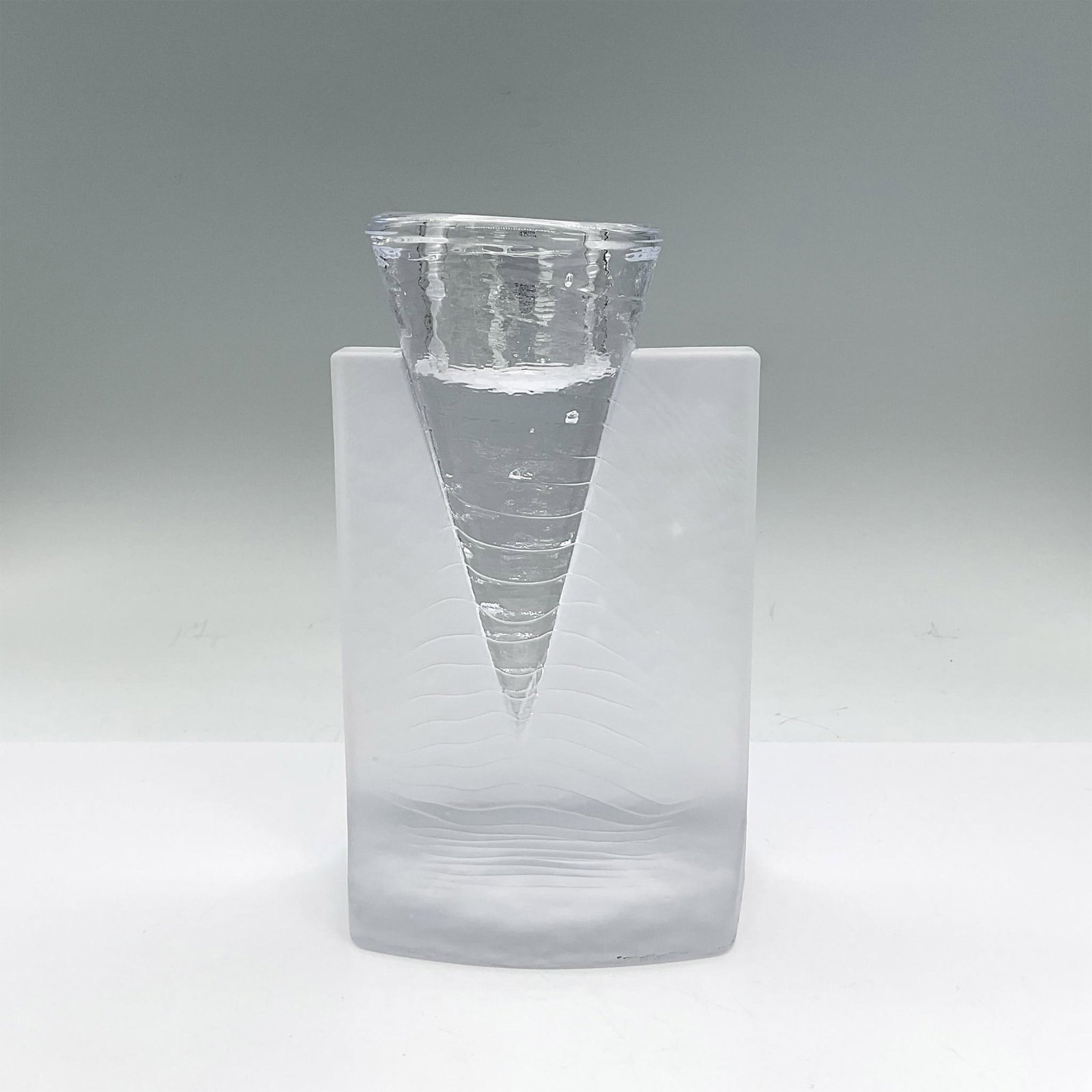 Kosta Boda Glass Candleholder, Ice Age: Elegant candleholder in matte and shiny clear glass with a conical segment for the candle, textured wave pattern. Kosta Boda etched mark. Artist: Kjell Engman Dimensions: 4.75"L x 4.25"W x 7.75"H Manu