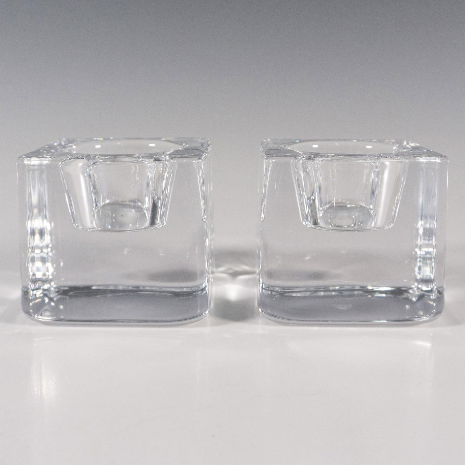 Pair of Orrefors by Goran Warff Candle Holders, Ice Cube: A crystal clear square votive candle holders. Orrefors stickered. This item has its original box: 3"L x 3"W x 3"H. Artist: Goran Warff Issued: 21st century Dimensions: 2.75"L x 2.75"W x 2.5"H Manufact