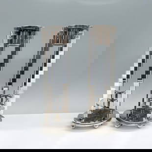 2pc Richard Meier for Swid Powell Candlesticks: A pair of silver-plated candlesticks featuring a sleek design, characterized by flat square bodies and rounded base. Marked Swid Powell. Marked RM. Marked Italy. Artist: Richard Meier Dimensions: 9"H