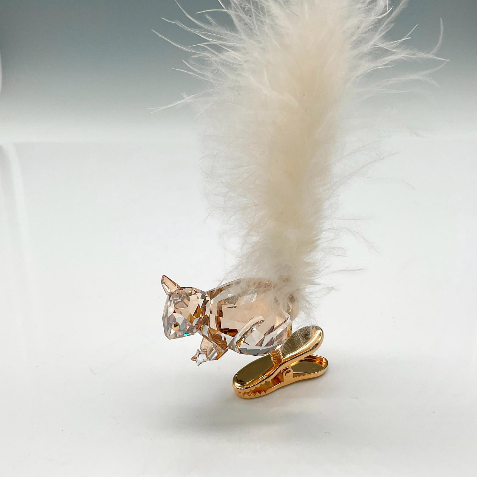 Swarovski Crystal Ornament, Winter Squirrel: Part of the Merry Christmas theme. Figural is designed in amber crystal holding a star with his crystal bushy feather tail attached to gold toned clip. Swarovski impressed mark. 1006040. This item has
