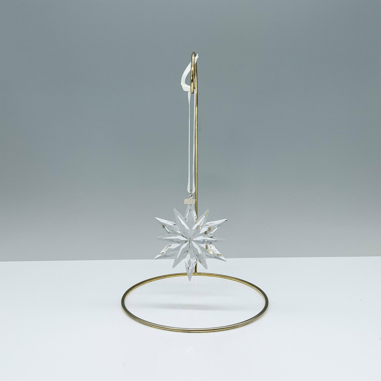 Swarovski Crystal Christmas Ornament 2011 Snowflake: A radiant clear crystal snowflake with 12 intricate points and a beautiful white satin ribbon joined by a tag engraved with 2011. Swarovski backstamp. This item has its original box. Dimensions of the