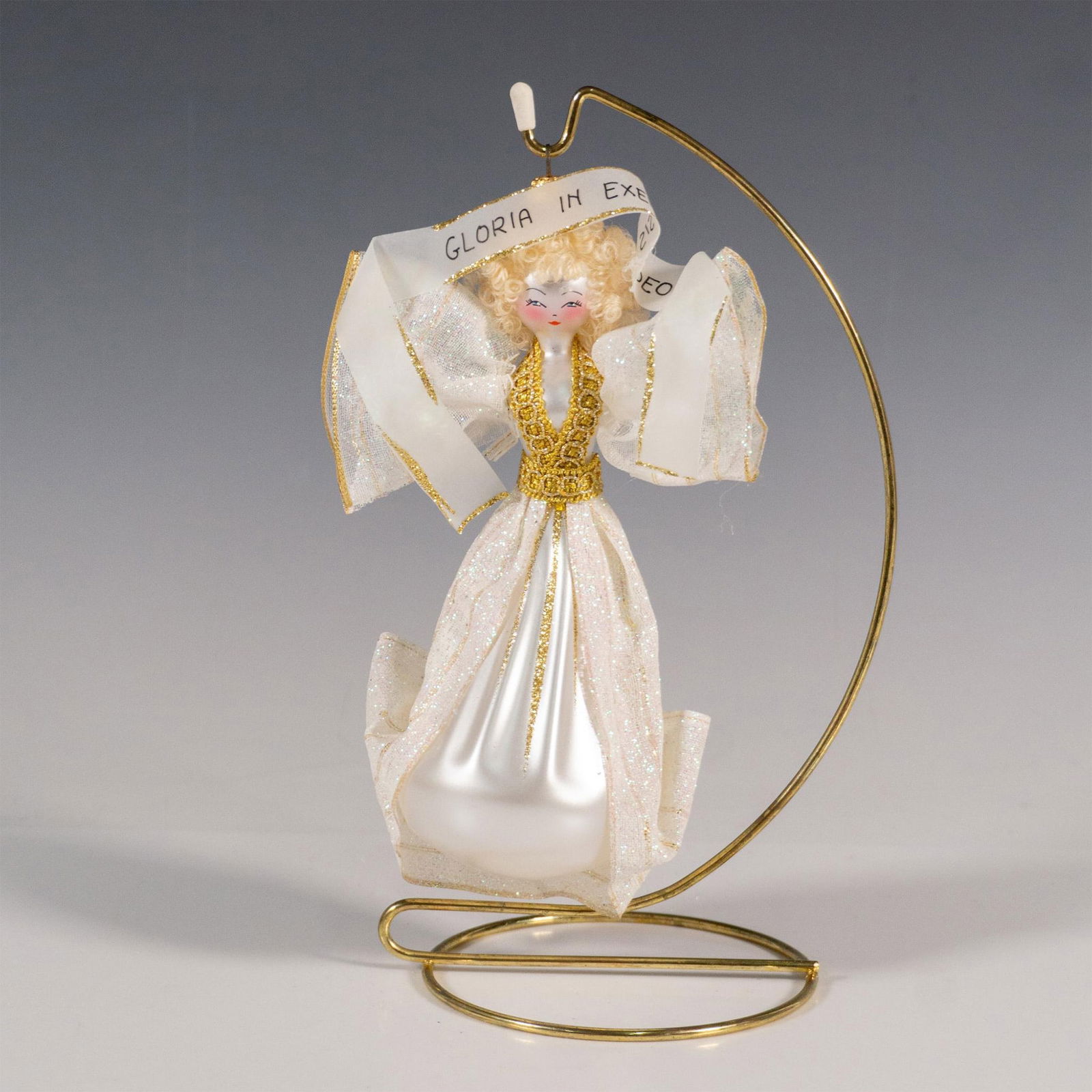 Glass Blown Christmas Ornament, Gloria in Excelsis Deo: This handcrafted European-style glass Christmas ornament features a doll-like angel adorned with a sparkling robe. The angel holds a ribbon reading Gloria in Excelsis Deo. Dimensions: 3.5"L x 2.5"W x