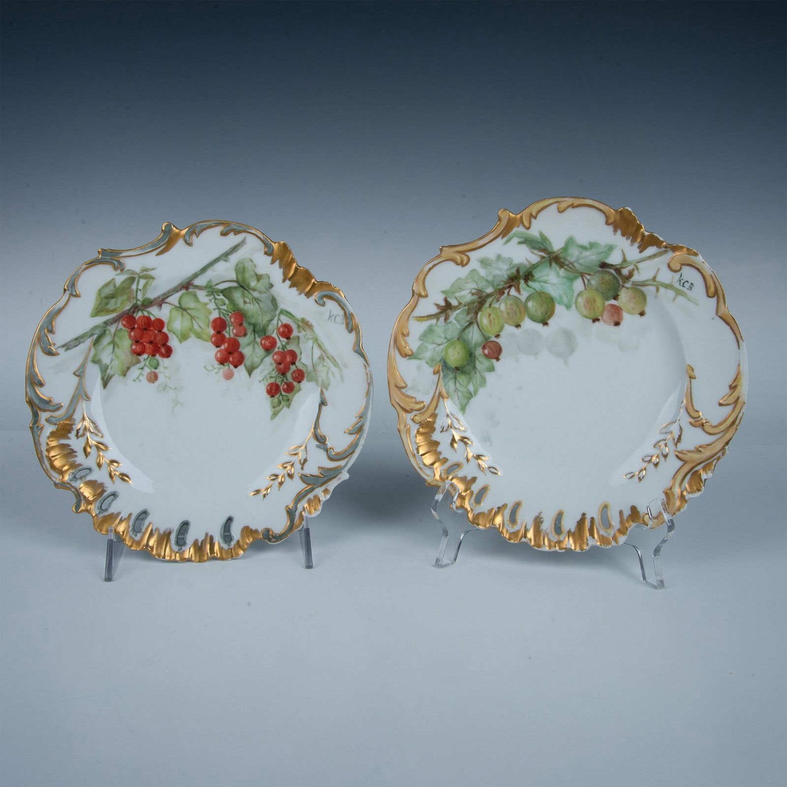 Pair of Delinieres & Bernardaud by Katie C. Brown Plates: A set of two Limoges porcelain cabinet or wall plates with golden and silvery painted trims. Each plate is hand painted with berries. Delinieres & Bernardaud backstamps. Artist signed on the front and