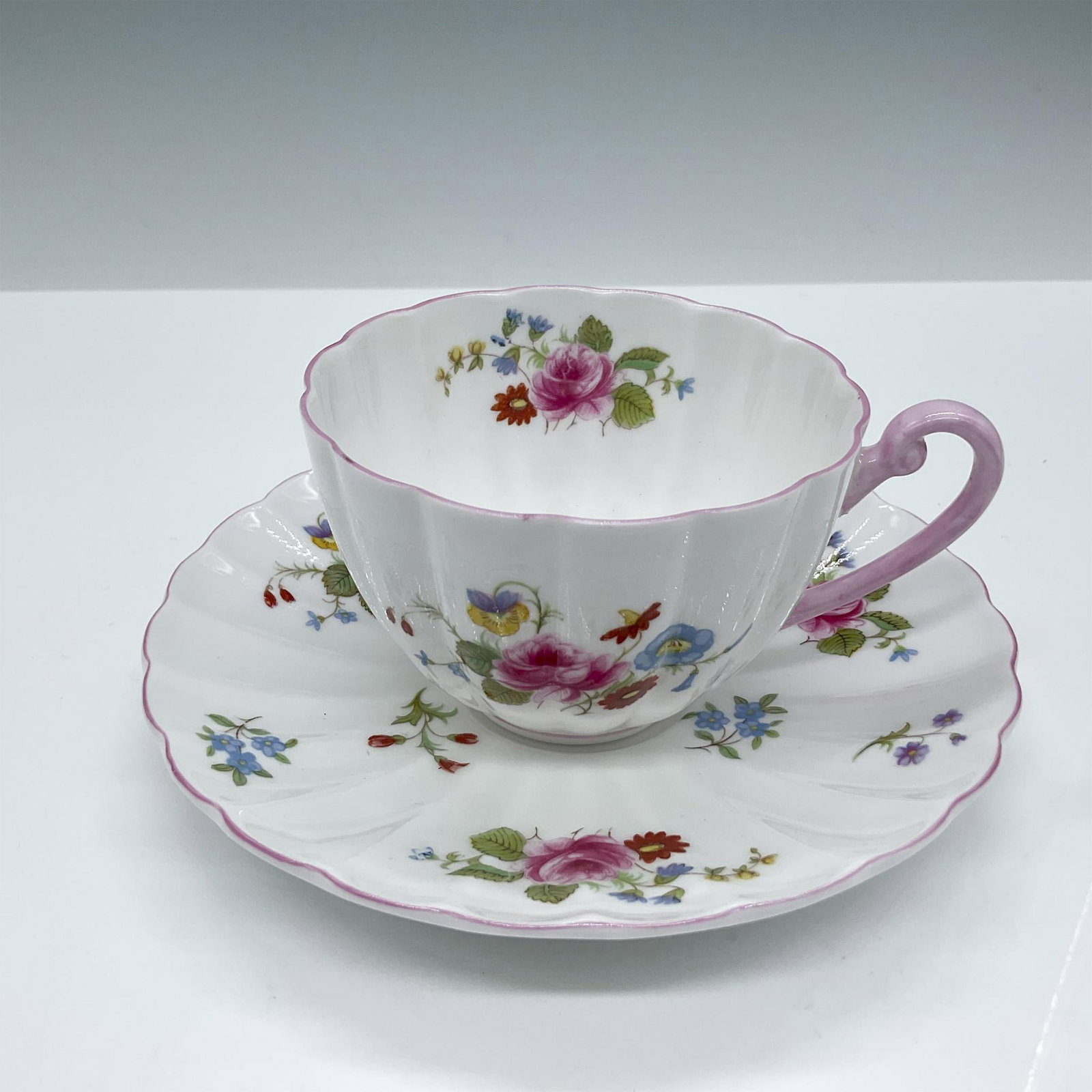 Shelley Bone China Tea Cup and Saucer Set, Rose & Red Daisy: This gorgeous fine Bone China set features colorful floral designs and pink accents. Shelley backstamp. Issued: 20th century Dimensions: Cup: 3.5''L x 4.25''W x 2.25''H; Saucer: 1''H x 5.5''dia Manufa
