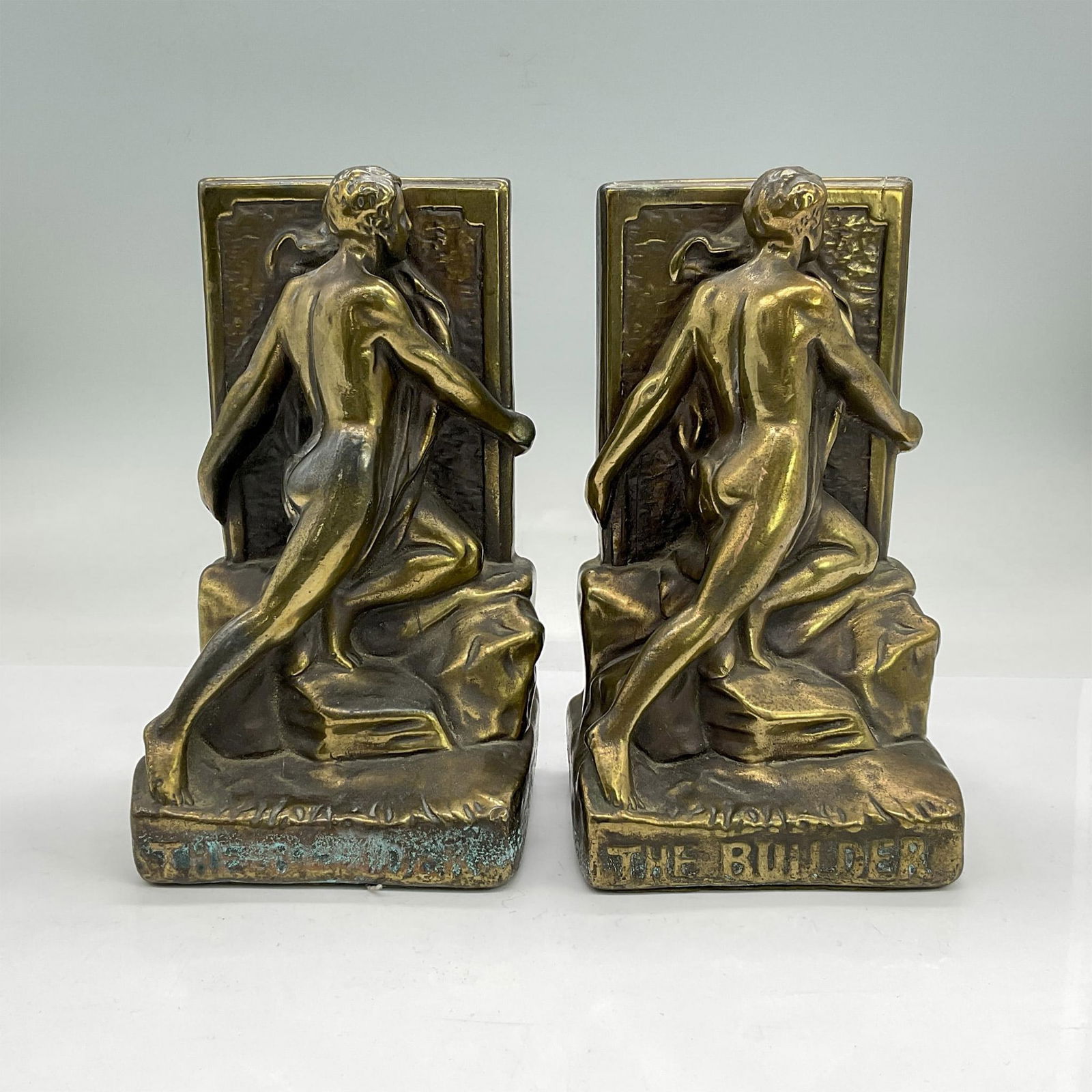 2pc Bronze Bookends, The Builder: Pair of bronze bookends modelled as a nude man holding on to the sides of the wall as he builds. Each is 4.25"L x 3.5"W x 7.5"H.