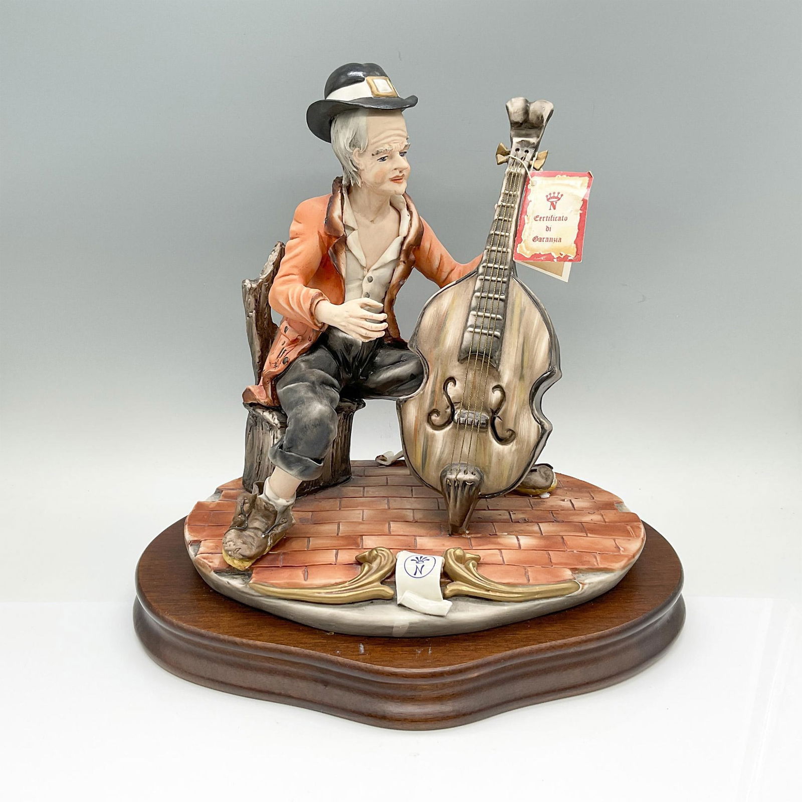 Capodimonte by Sartori Porcelain Figurine, The Celloist: Hand painted detailed figure of a vagabond playing the cello. Marked Capodimonte and Sartori Made in Italy. Attached to a wooden base. Artist: Sartori Dimensions: 11.5"L x 8.5"W x 11"H Manufacturer: C
