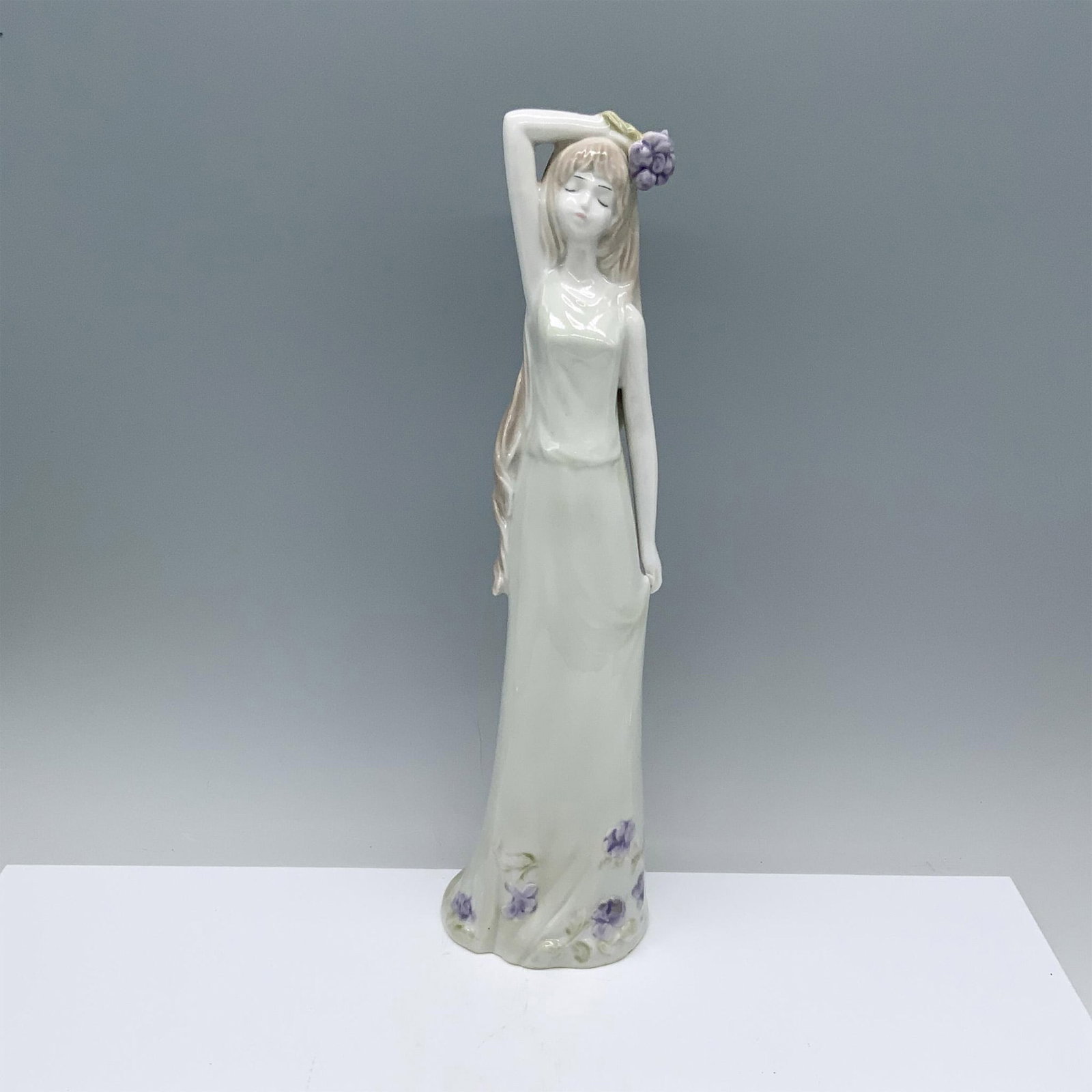 Lladro Style Girl With Flowers Figurine: Glossy figurine of a girl in a green dress with purple flowers. Dimensions: 3.5"L x 3.25"W x 13"H