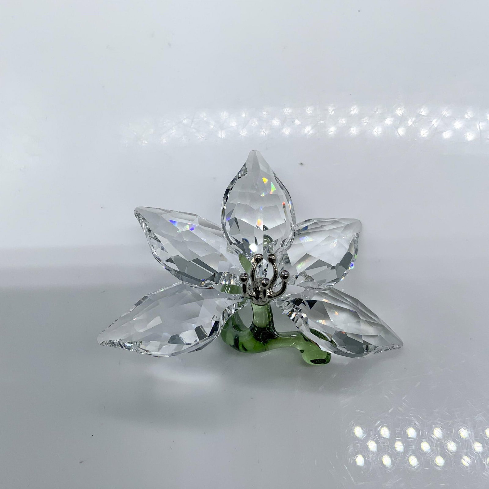 Swarovski Crystal Society Figurine, Orchid 1142858: Exclusive SCS new member or renewal piece. Clear crystal flower with a green stem. Swarovski acid marked. This item has its original box which measures 3.75'L x 3.75"W x 1.5"H. Artist: Elisabeth Adame