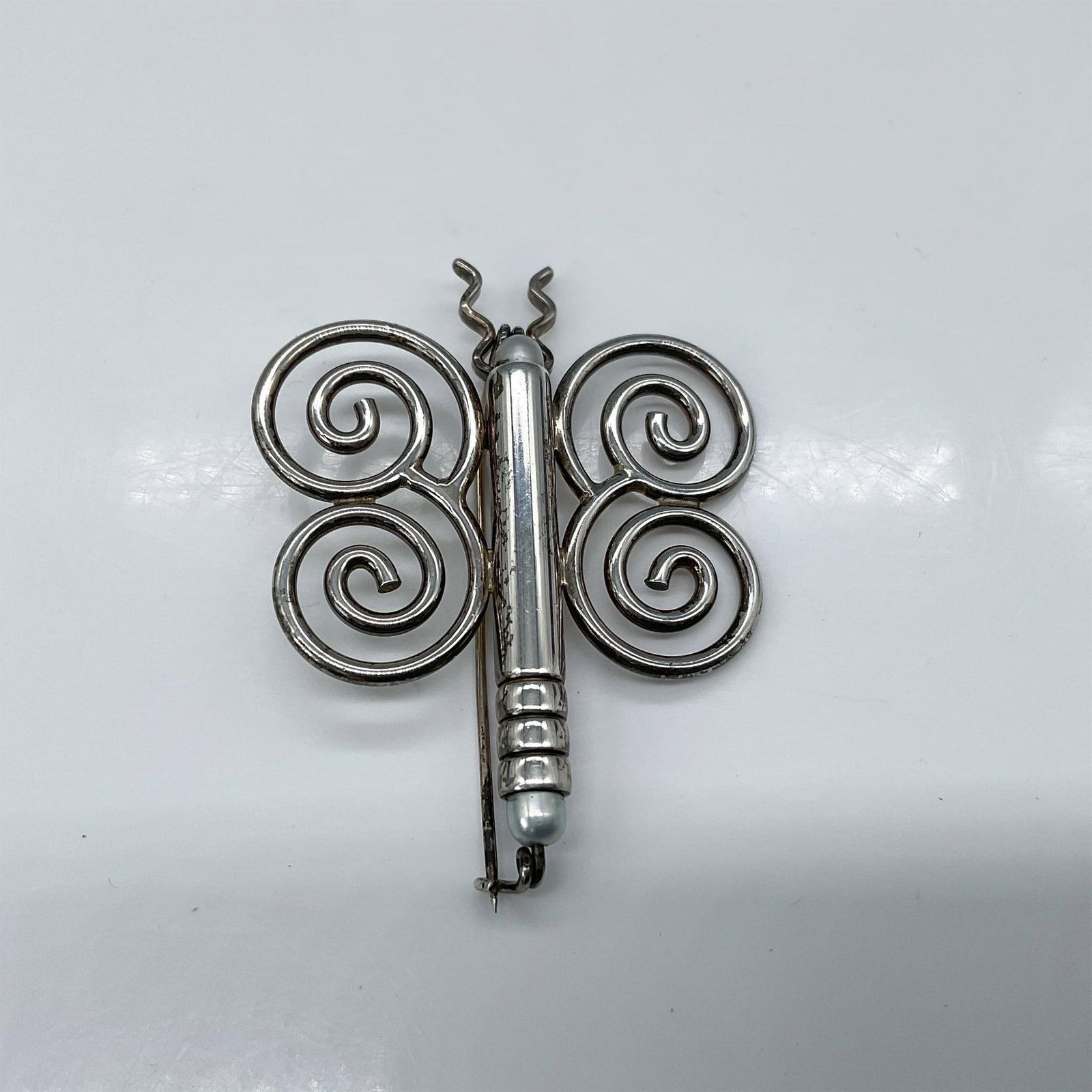 J.H. Breakell & Co. Sterling Silver Brooch, Butterfly: This modernistic representation of a butterfly features pearl-like embellishments on its head and tail. Total weight: 16 grams. Dimensions: 1.75"L x 0.5"W x 2.5"H