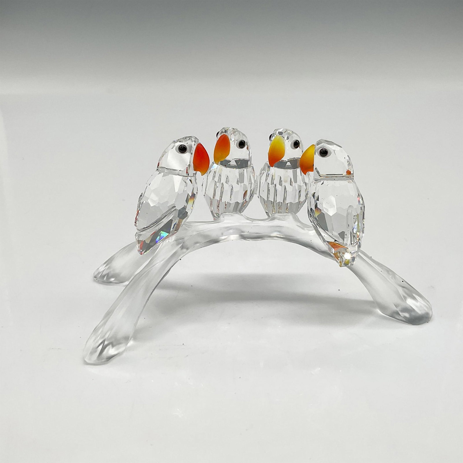 Swarovski Silver Crystal Figurine, Baby Lovebirds: Part of the Feathered Beauties theme group. Faceted clear crystal birds perched on a satin crystal branch. The Lovebirds accented by their Fire Opal crystal beaks and Jet crystal eyes. Swarovski backs