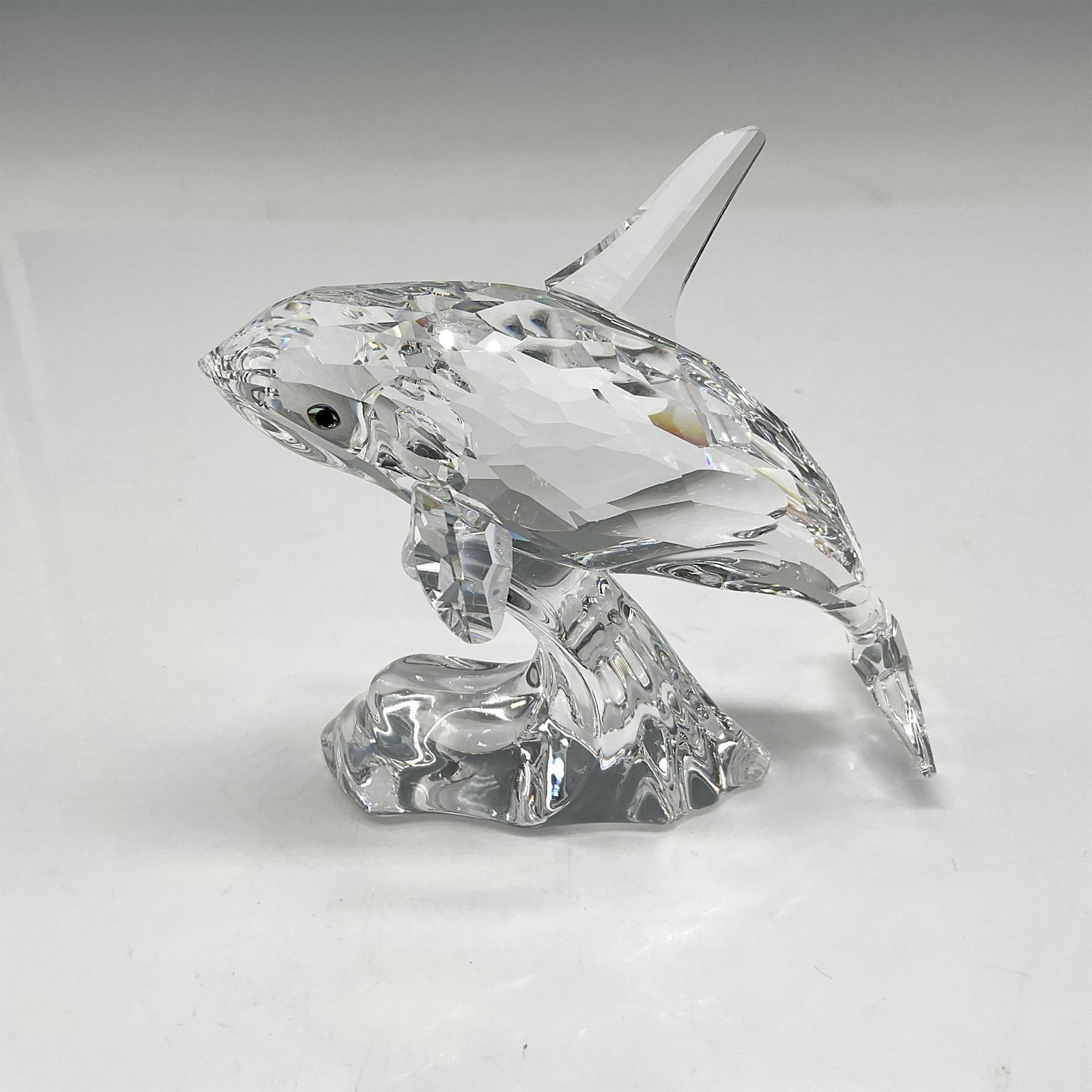 Swarovski Silver Crystal Figurine, Orca (Killer Whale): Lovely crystal figural in motion jumping a wave, looking out with his aqua crystal eyes. Swarovski backstamp. 7644 000 009. This item has its original box: 7.5"L x 8"W x 4"H. Artist: Michael Stamey Is
