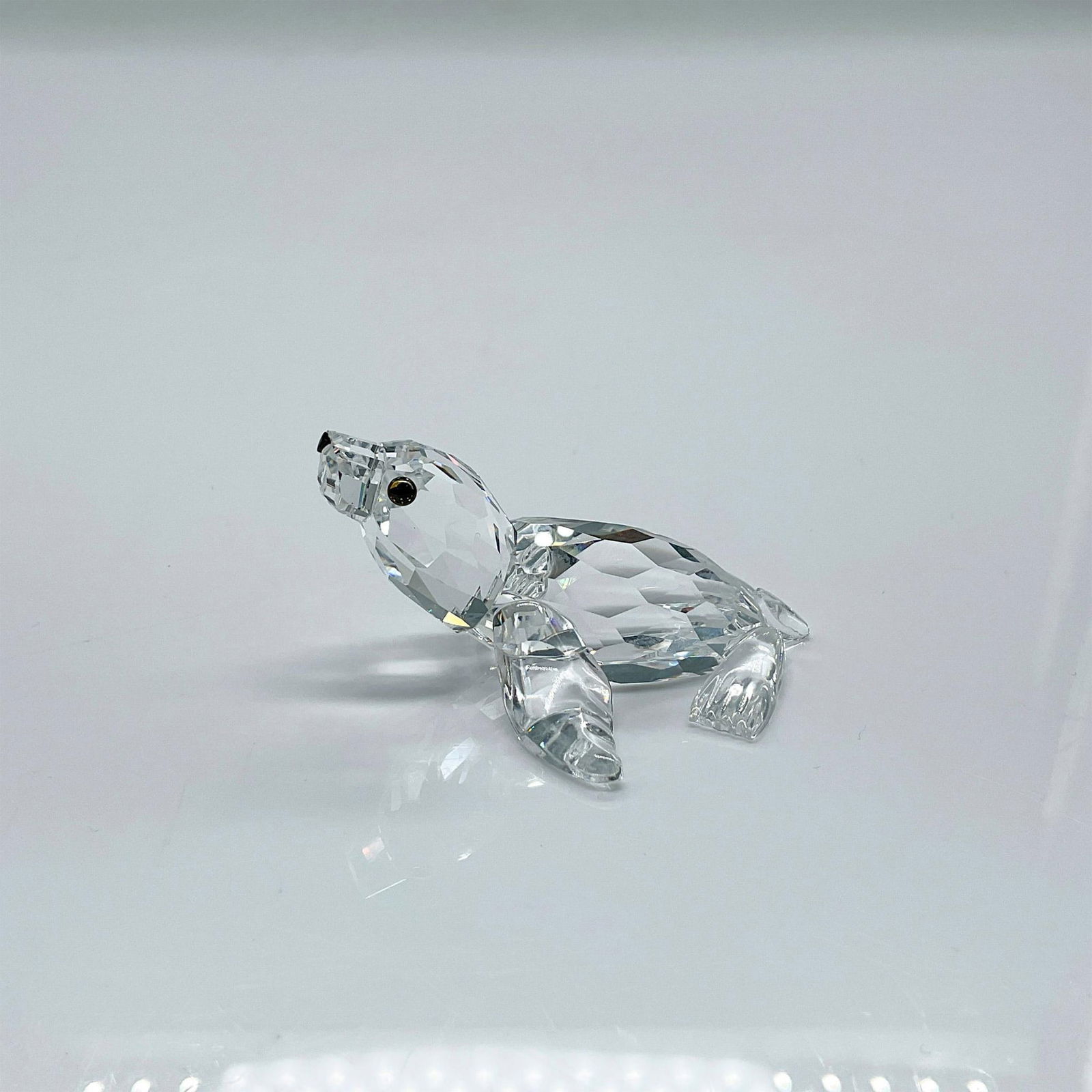 Swarovski Silver Crystal Figurine, Sea Lion: Clear faceted crystal figure of a sea lion with blue/green eyes, black nose. Part of the Aquatic Worlds collection. Swarovski mark. This item has its original box: 2.5"H x 3.25"dia. Issued: 1998-2010