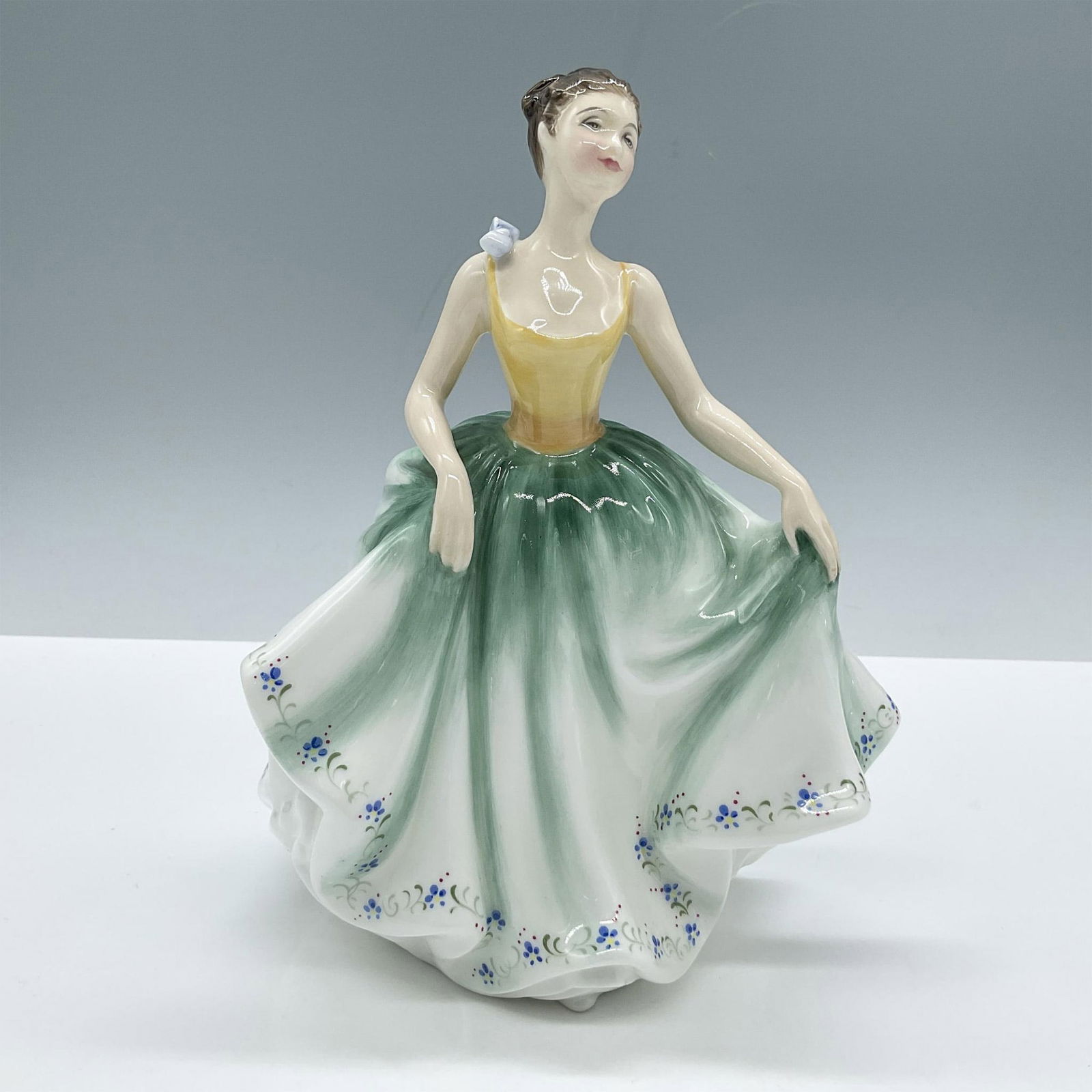 Cynthia - HN2440 - Royal Doulton Figurine: Glossy porcelain. Features a girl in a green and yellow dress adorned with blue flowers. Royal Doulton backstamp. Artist: M. Davies Issued: 1984 - 1992 Dimensions: 4''L x 4''W x 8''H Manufacturer: Roy