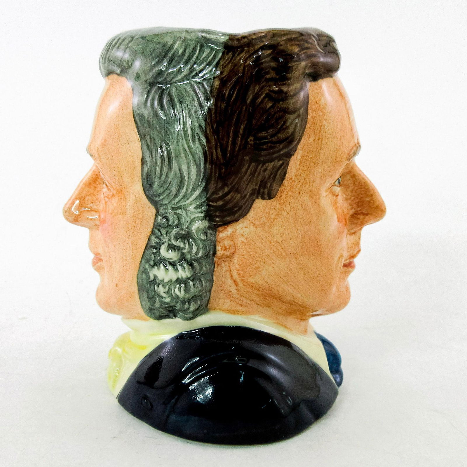 Sir Henry / Michael Doulton D6921 - Small - Royal Doulton Character Jug: Henry- Grey hair; yellow cravat; Michael- Brown hair; dark blue suit; white shirt; light blue tie. This two-faced jug was a special edition jug issued to mark Michael Doulton's personal appearances at