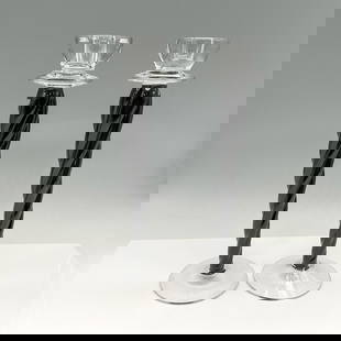 Pair of Kosta Boda Art Glass Candle Holders, Cypress: Striking combination of clear and onyx glass with twisted stem. Clear glass holder and base. Kosta Boda. Artist: Ann Wahlstrom Issued: 21st century Dimensions: 12"H x 4" dia. Manufacturer: Kosta Boda