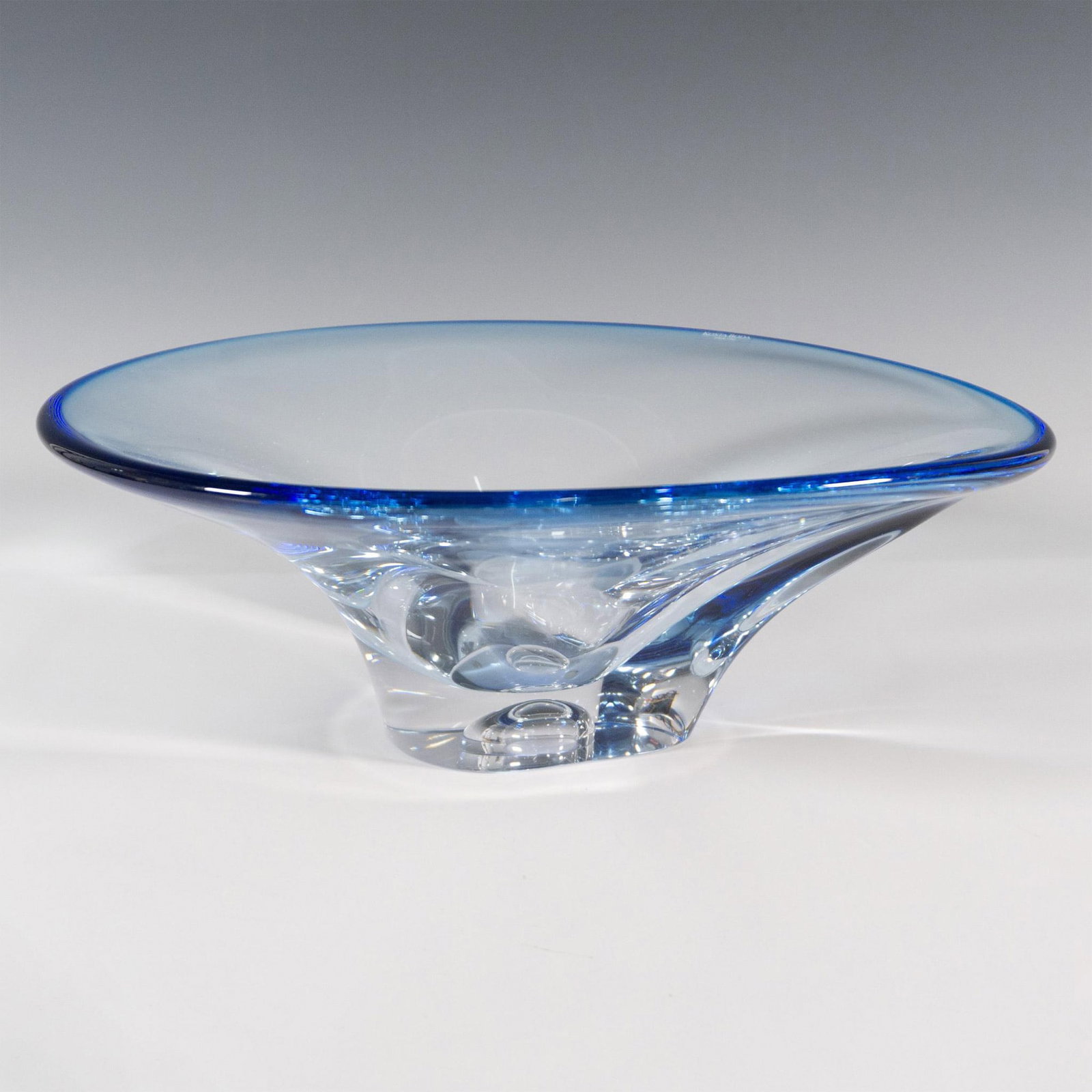 Kosta Boda Crystal Decorative Bowl, Sapphire: Rare crystal footed wide bowl, features a gradient blue effect on the rim and a beautiful oval shape. Kosta Boda engraved signature. Artist: G. Warff Dimensions: 12''L x 11''W x 4.5''H Manufacturer: K