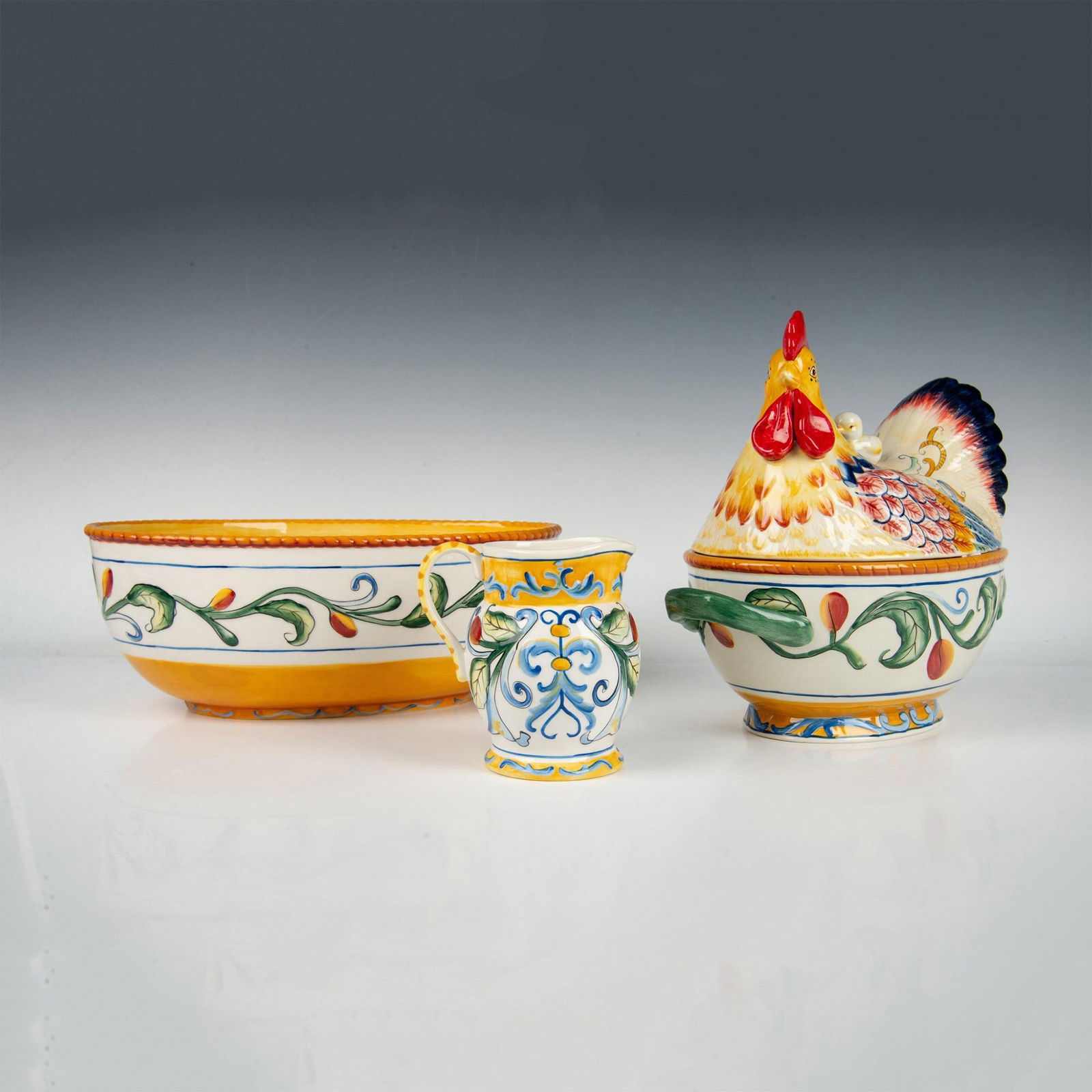 3pc Fitz and Floyd Pottery Tableware, Ricamo: Hand painted oval vegetable bowl, chicken lid tureen, and creamer. Vibrant polychrome colors featuring berries, and chickens. Fitz and Floyd backstamp. Oval bowl: 12.25"L x 8"W x 4.5"H. Chicken tureen