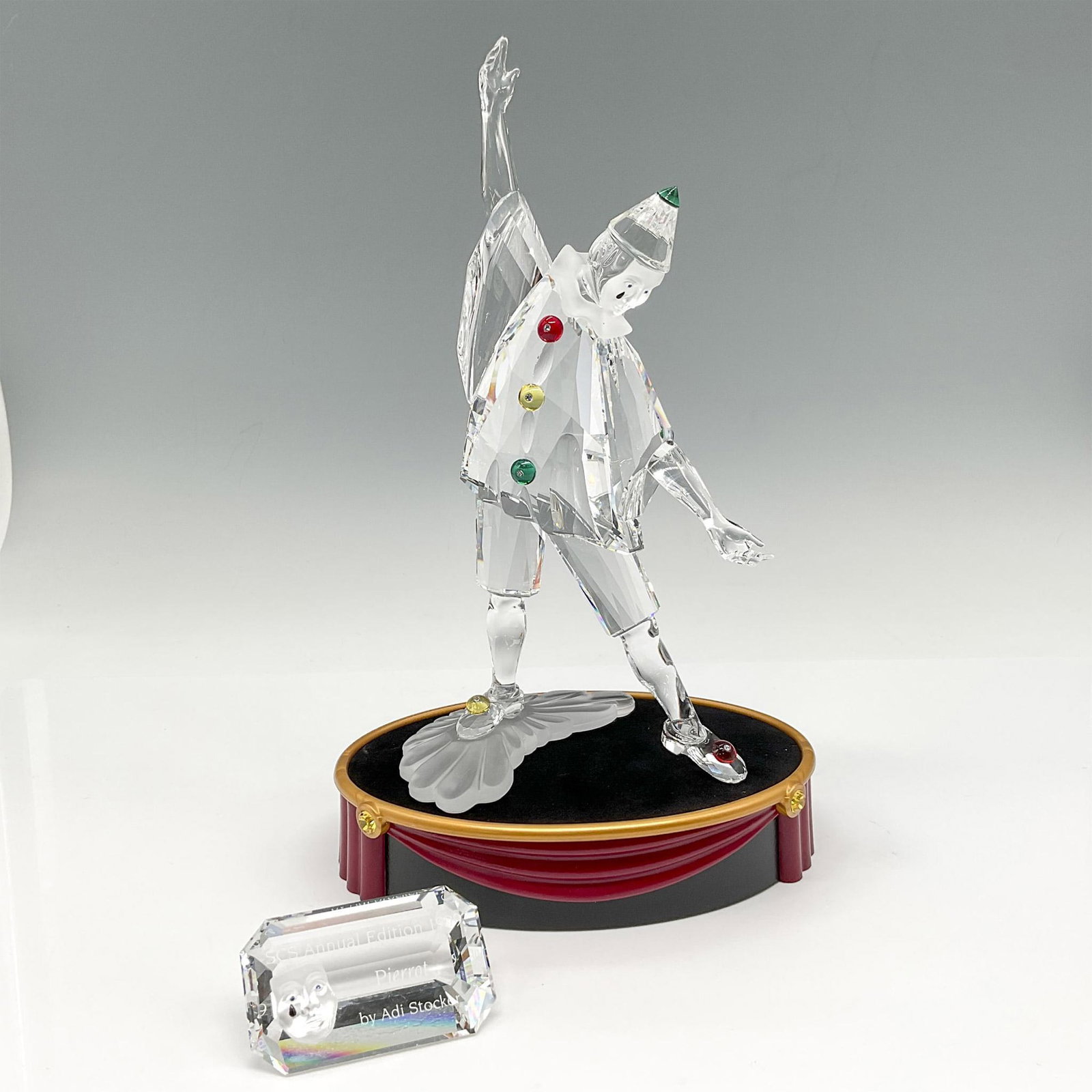 Swarovski SCS Figurine, Masquerade Pierrot + Base, Plaque: Figural is first piece of the Masquerade trilogy. Created with colored crystal on his clothing, hat and shoes. Along with blue crystal eyes and a black tear drop on his cheek. Satin crystal was used o