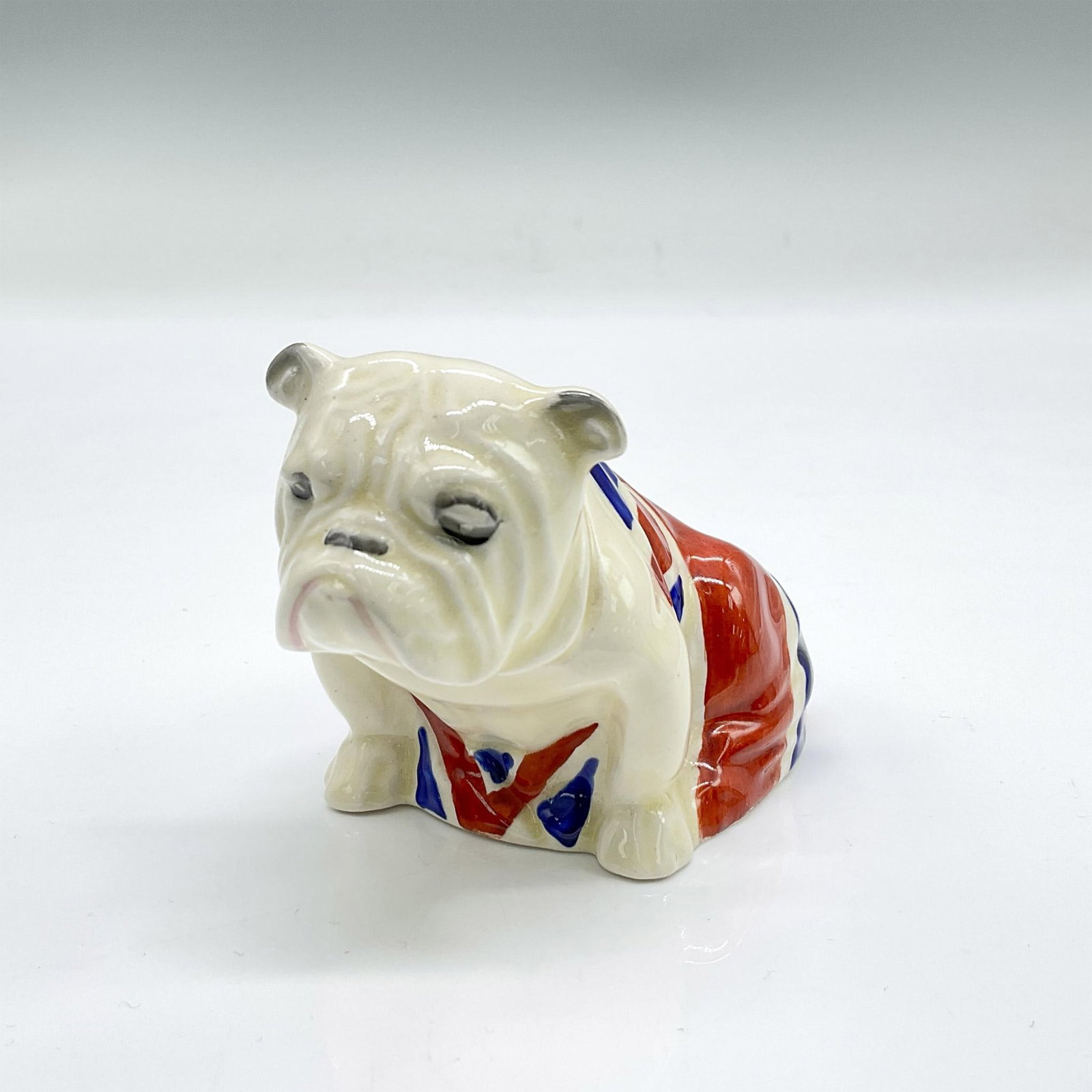 Bulldog Union Jack, Small - D5913 - Royal Doulton Figurine: Figure of a seated bulldog draped with the Union Jack flag. Royal Doulton backstamp. Issued: 1941 Dimensions: 3.5"L x 2"W x 2.25"H Manufacturer: Royal Doulton Country of Origin: England