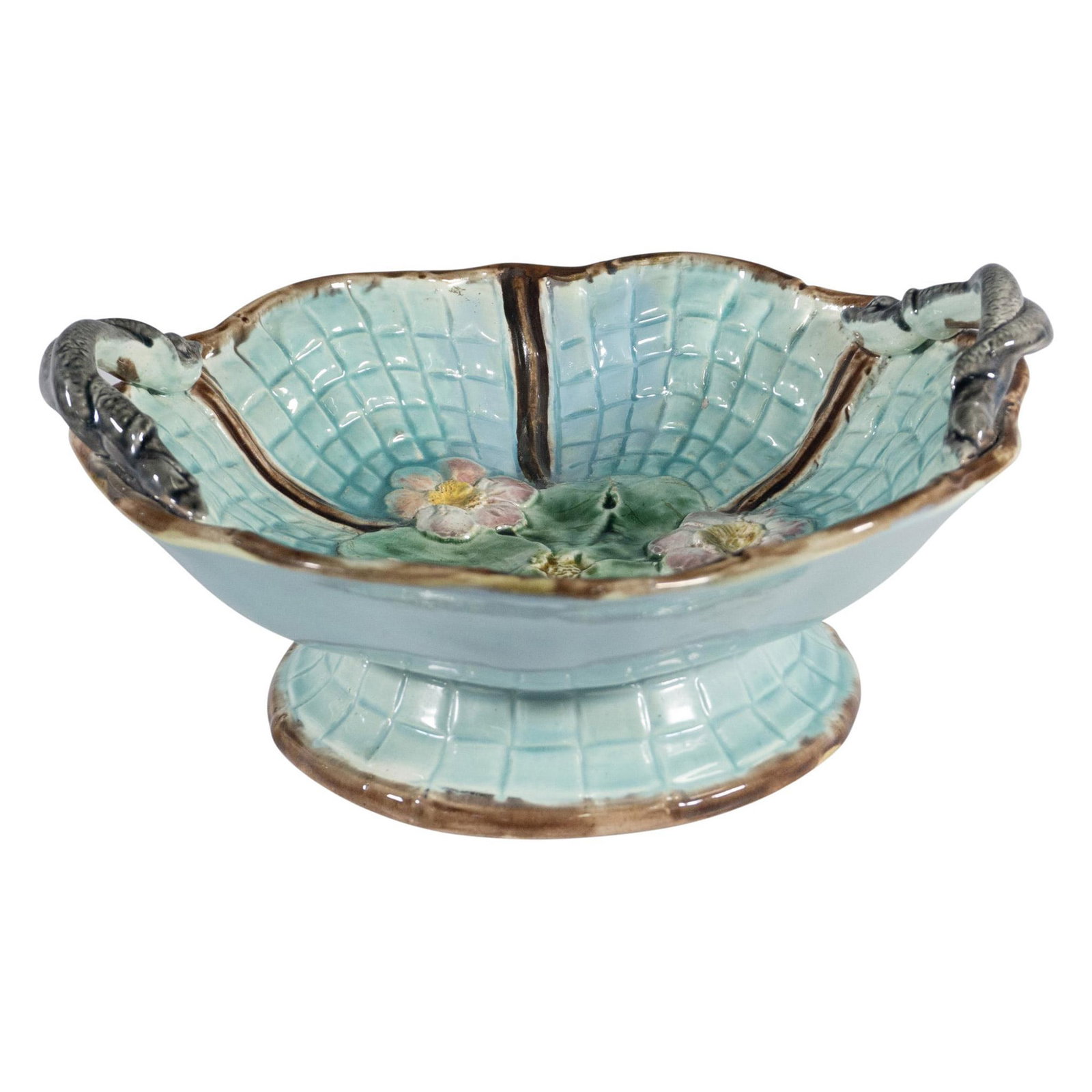 Majolica Raised Dish with Eels Blossoms and Basketweave: This exquisite dish is raised by a pedestal, showcasing blue-green, brown, pink, and green coloration throughout. At the bottom of the dish, beautifully detailed flowers and leaves adorn a net or bask