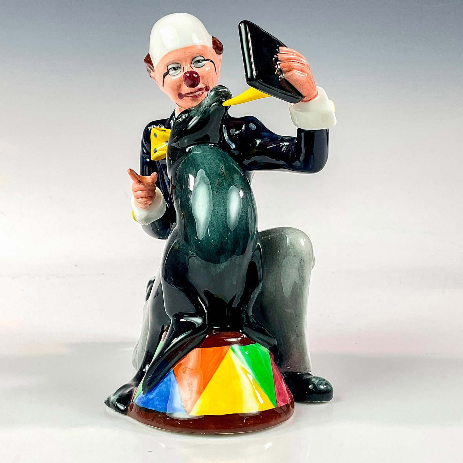 Partners HN3119 - Royal Doulton Figurine: Clown and sea lion posing. Black, blue, and grey coloration. Series: Clowns. Royal Doulton backstamp. Artist: Alan Maslankowski Issued: 1990 - 1992 Dimensions: 6.75"H Manufacturer: Royal Doulton Coun